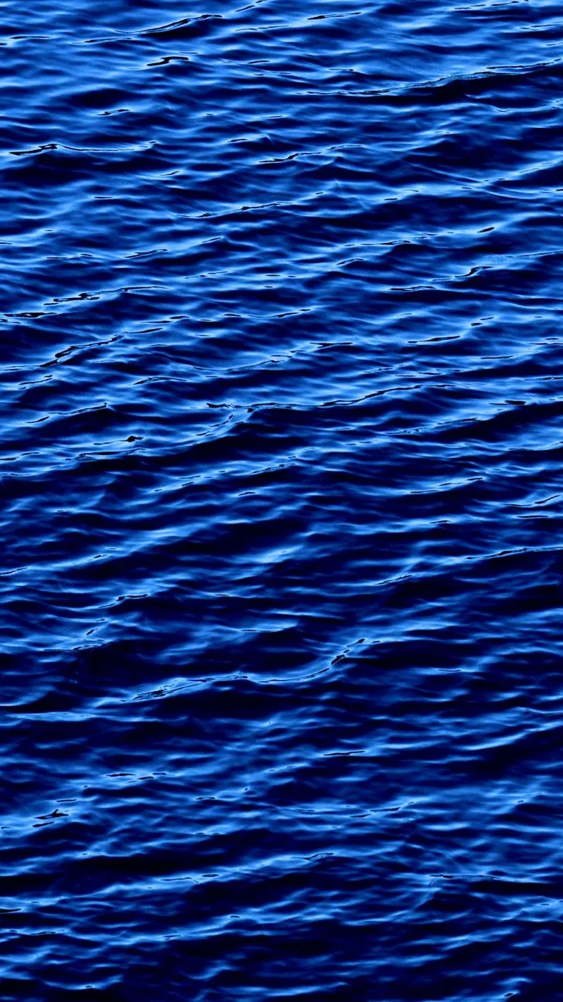 Superficie del mar con olas en tonos azules profundos y reflejos de luz.