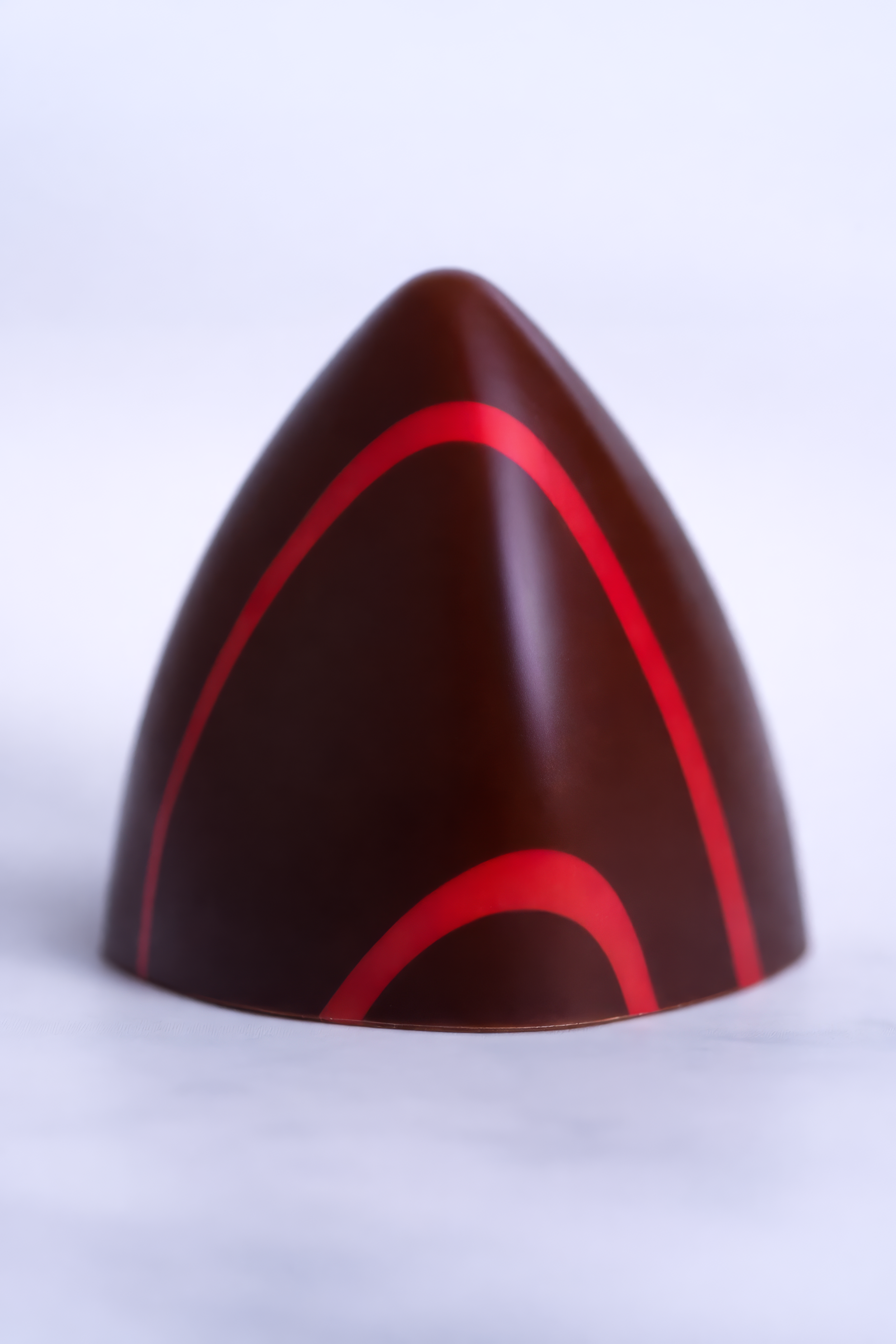 Chocolate en forma de arco con líneas rojas, sobre fondo blanco.