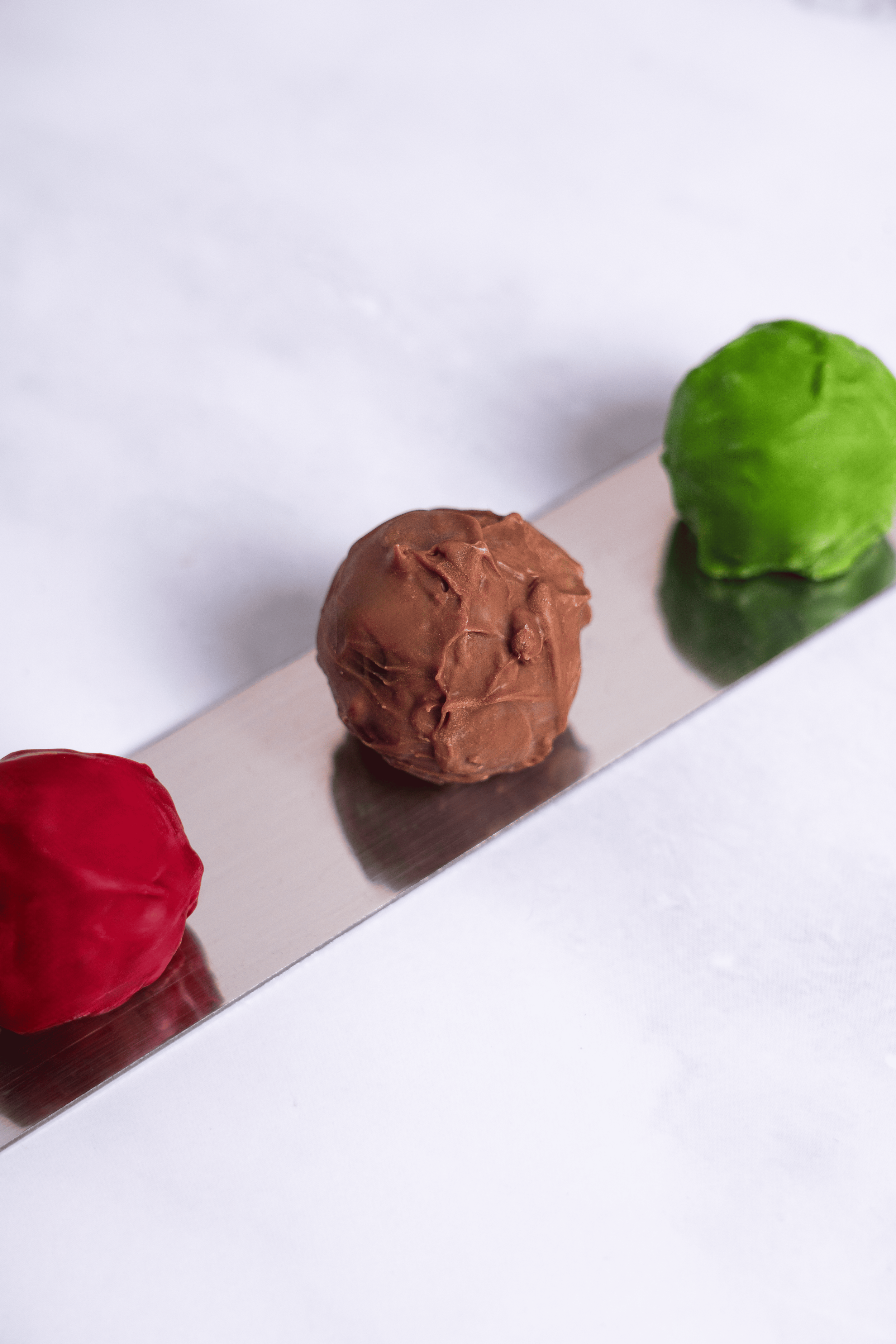 Tres bolas de diferentes colores (roja, marrón y verde) colocadas sobre una lámina metálica.