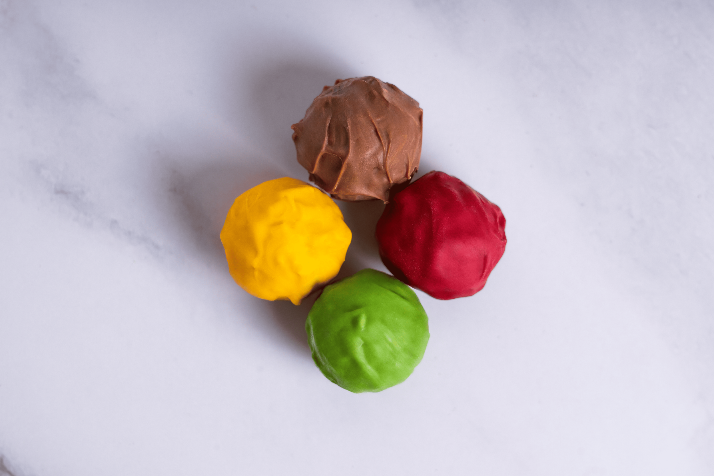 Cuatro bolas de differentes colores y texturas en un fondo blanco, una amarilla, una verde, una roja y una marrón.