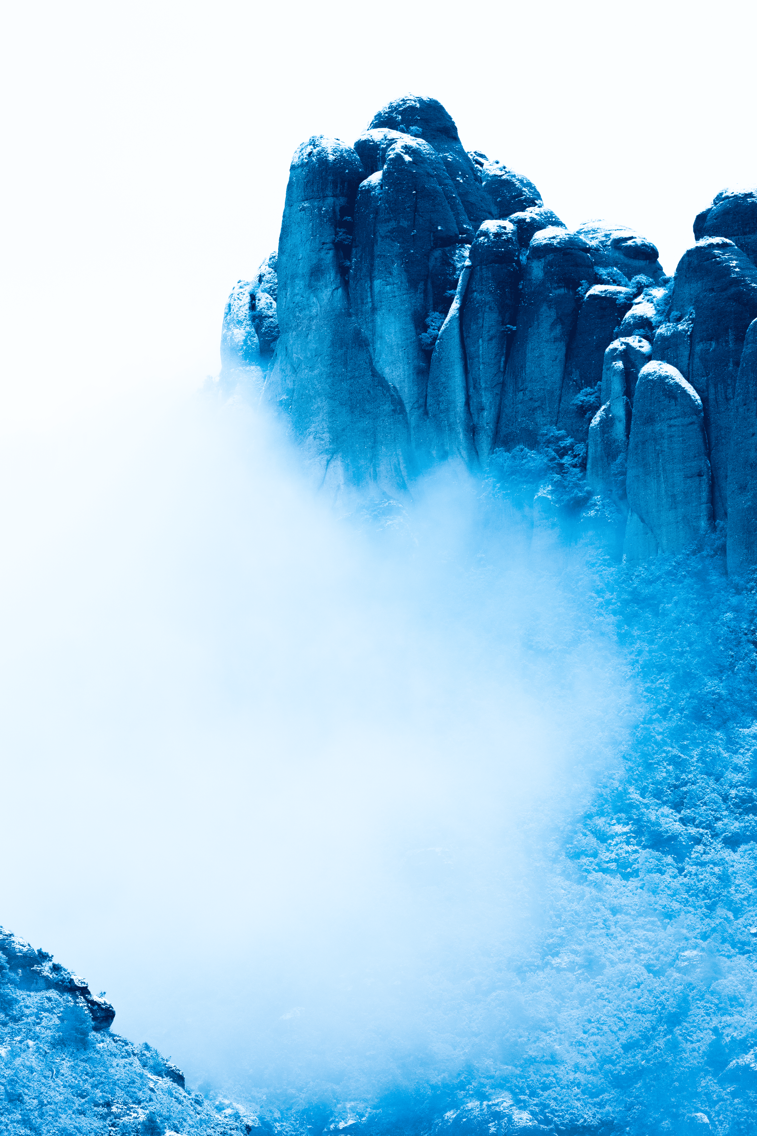 Montañas rocosas cubiertas de nieve con niebla en el fondo.