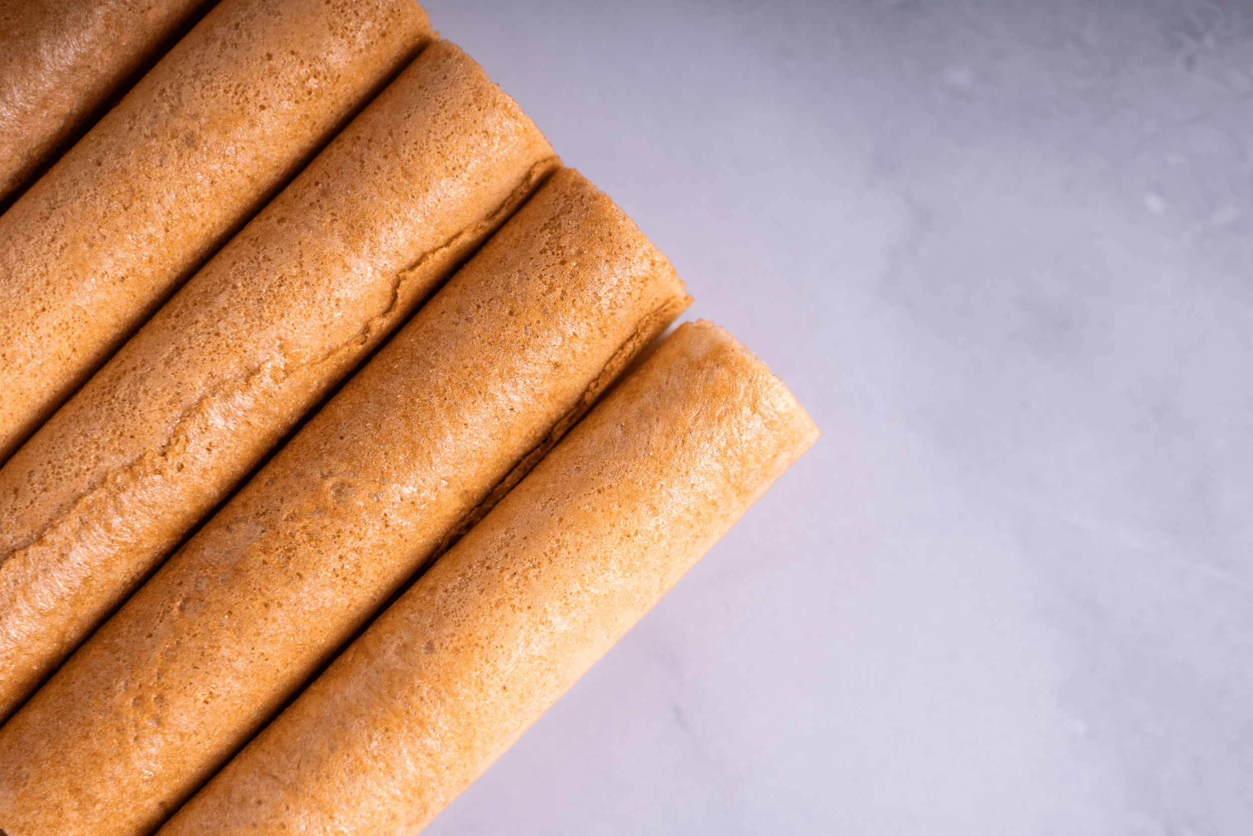 Cuatro tortillas de trigo apiladas sobre una superficie gris.