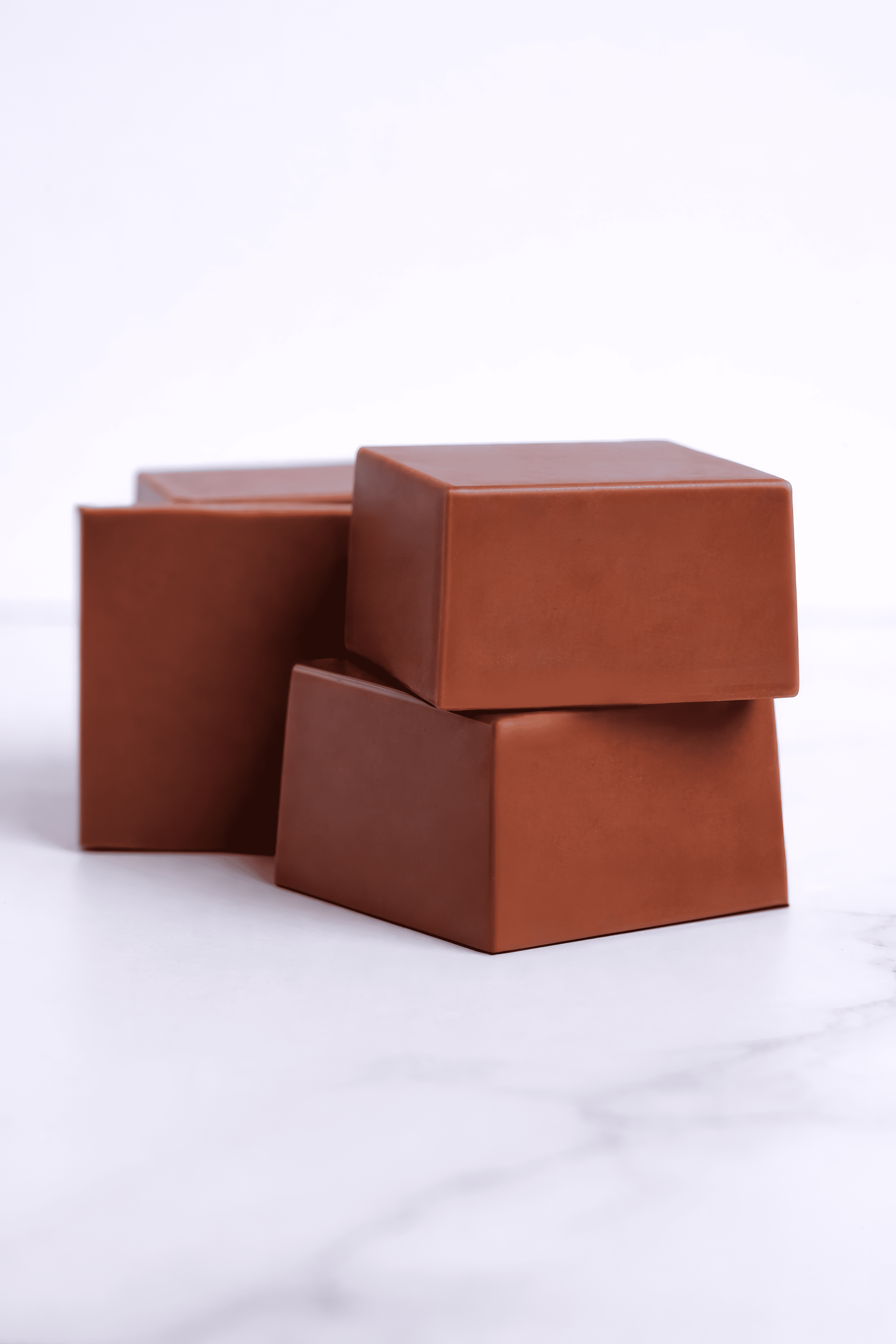 Cuatro cajas de color marrón apiladas una sobre otra en una superficie blanca.