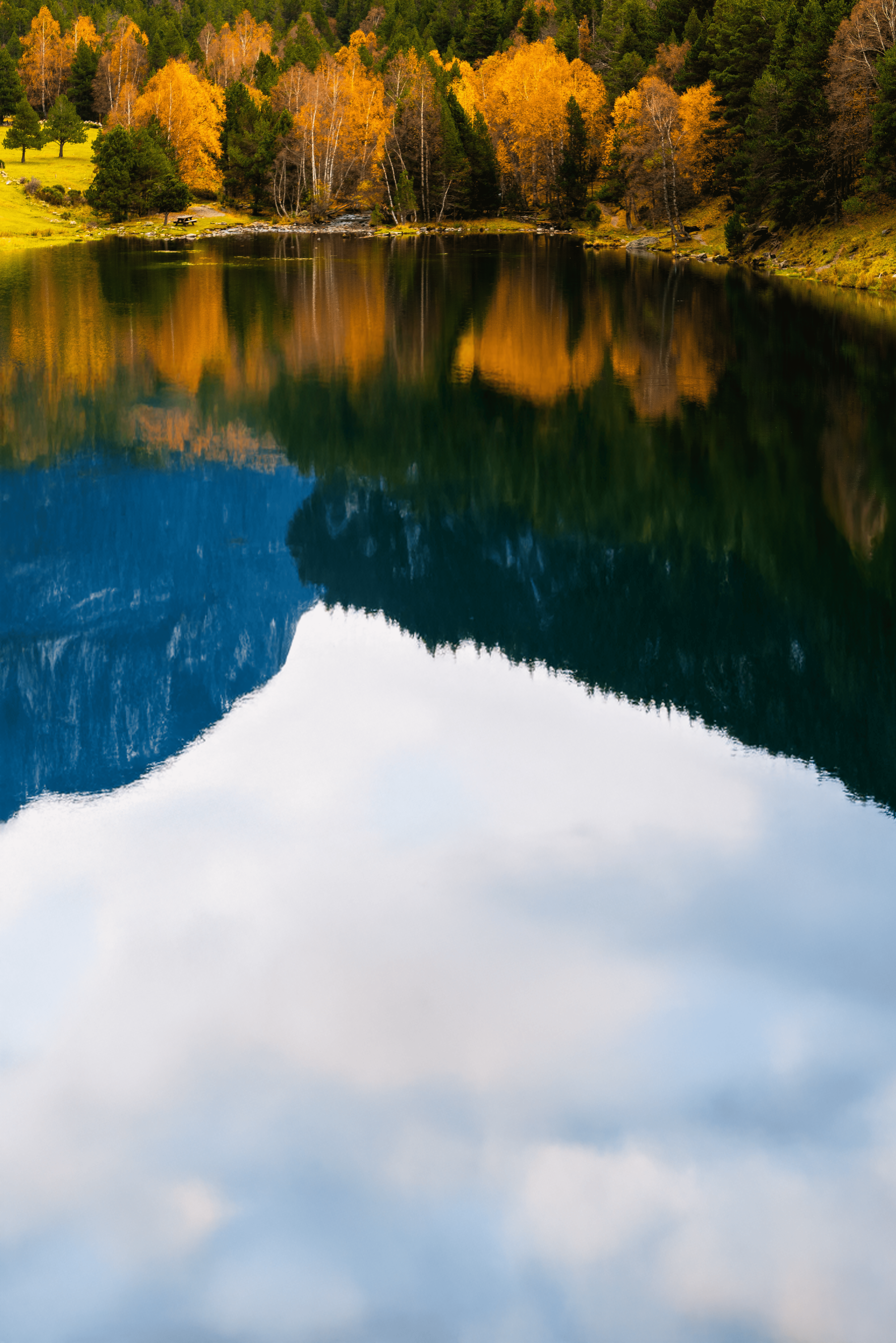 Reflejo de árboles otoñales y montañas en un lago