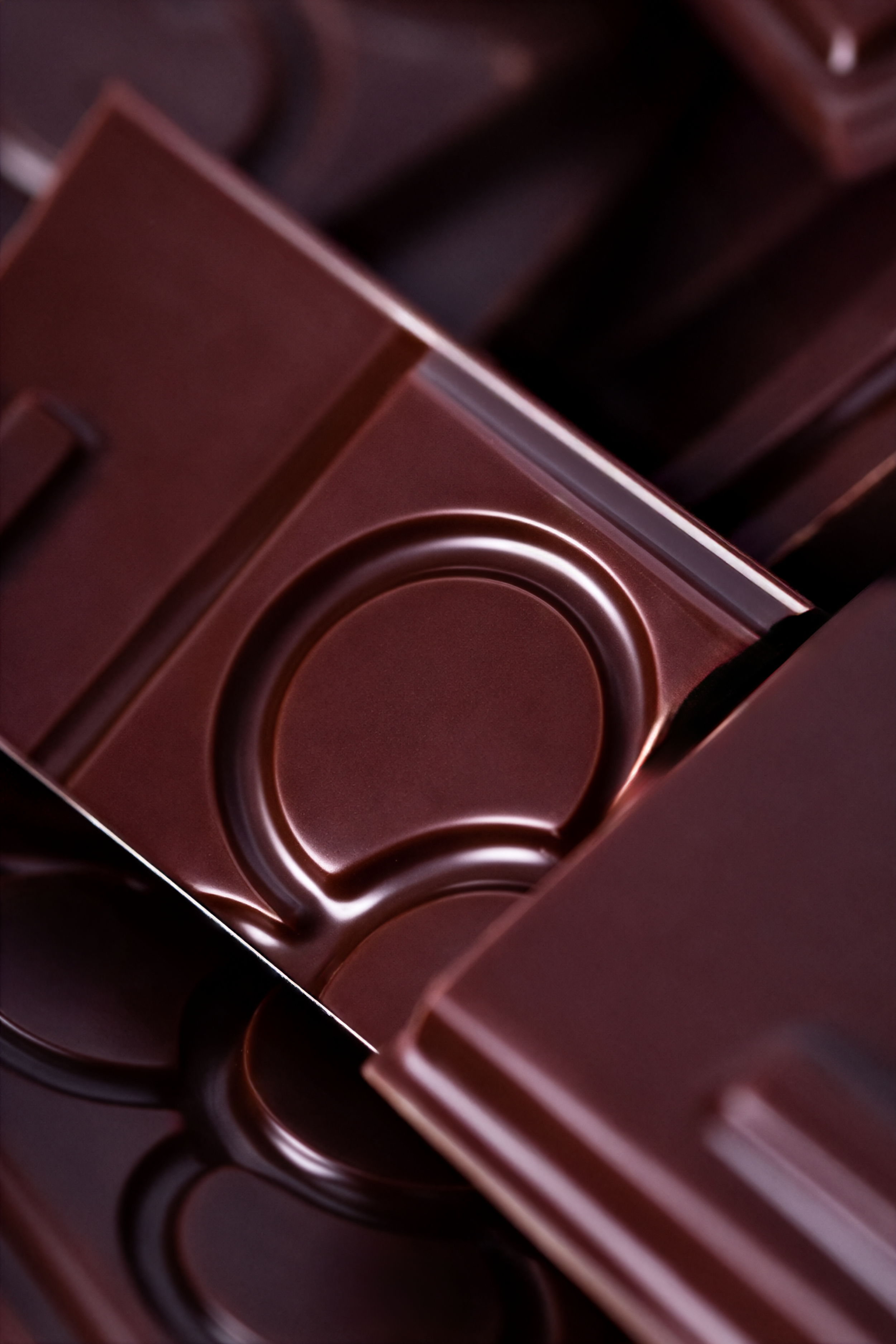 Imagen de varias cajas de chocolates de color marrón oscuro, con un diseño estructurado en círculos y líneas.