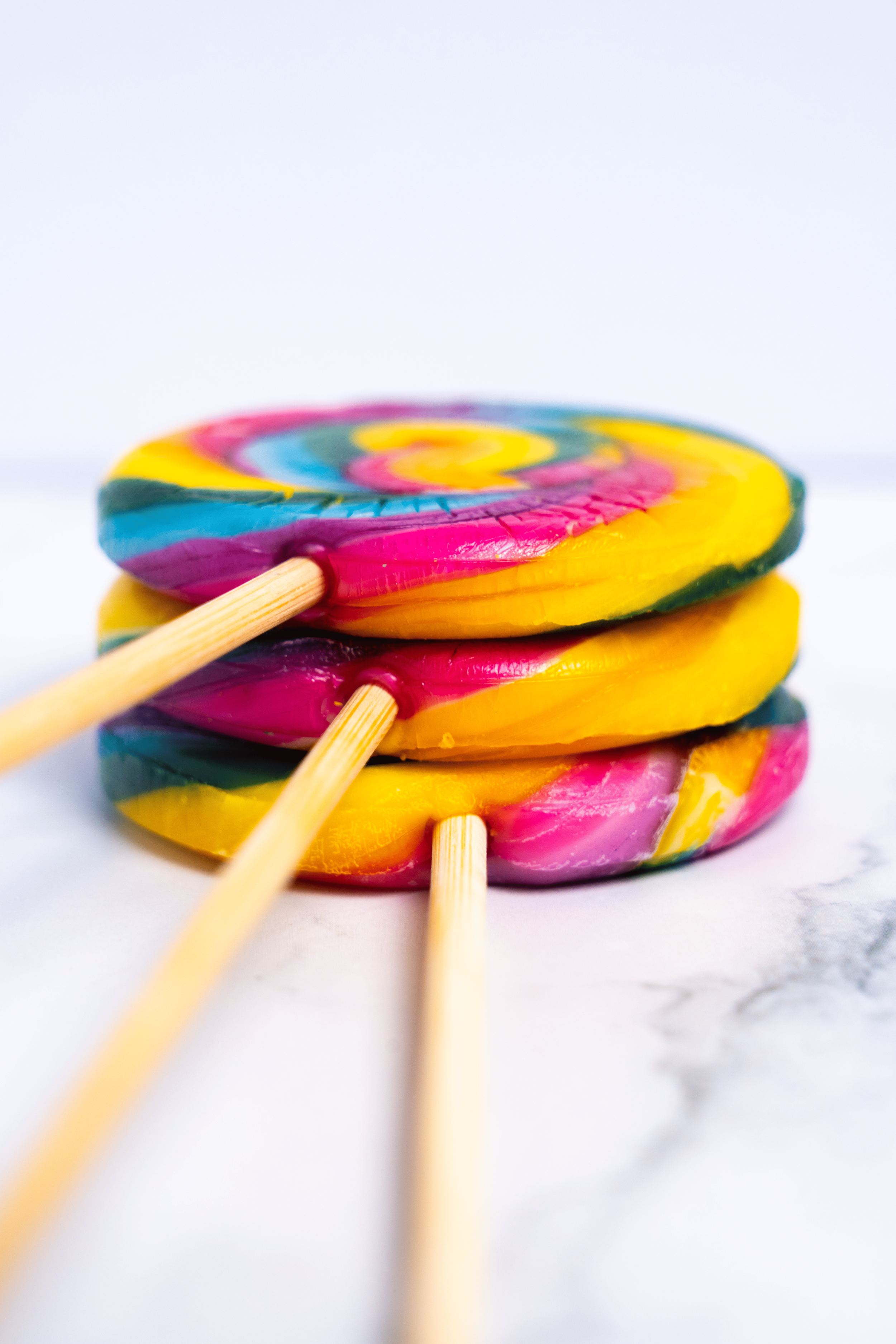 Paletas de caramelo de colores brillantes apiladas con palitos de madera.