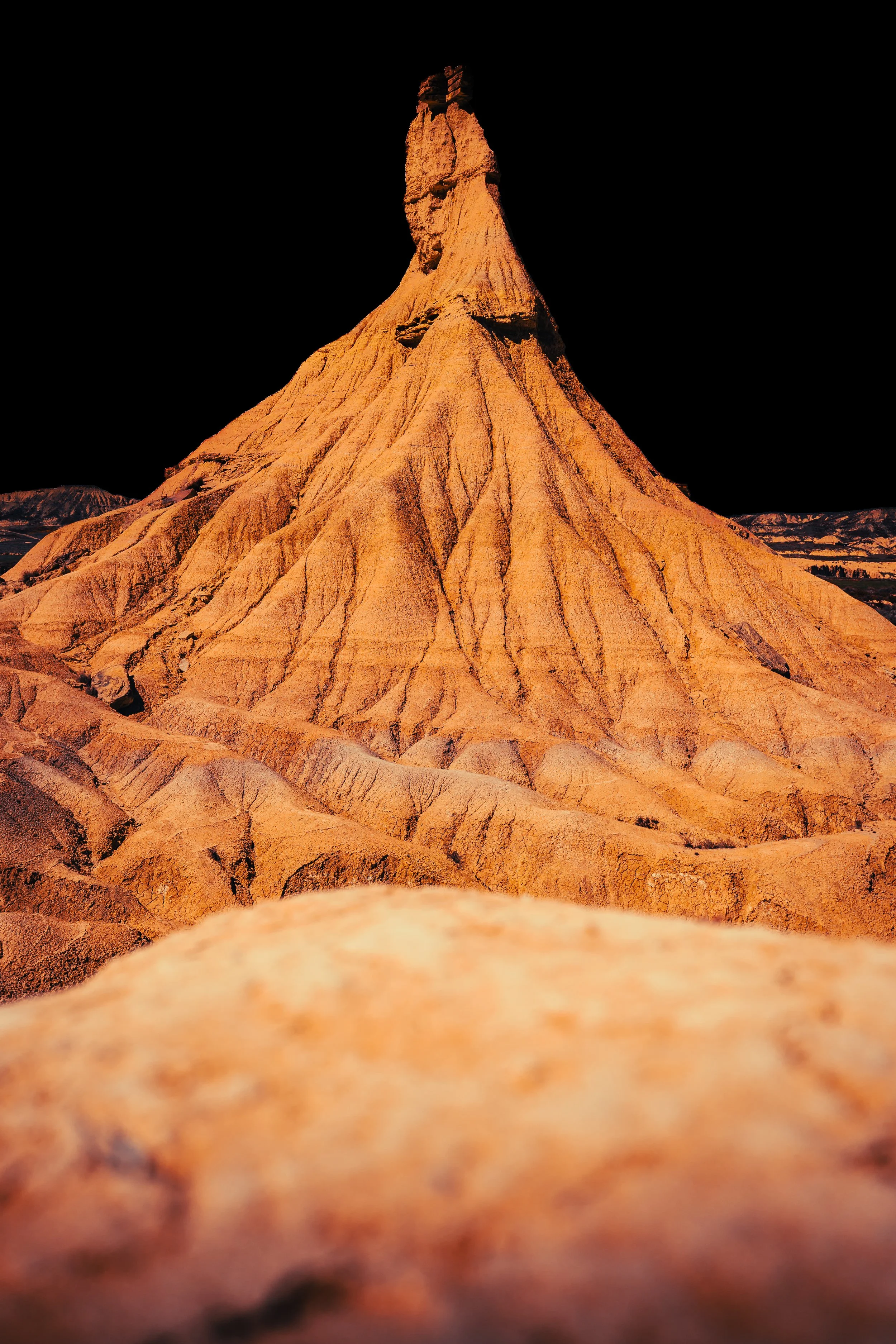 Formación rocosa con forma de rostro humano en un paisaje desértico al atardecer.