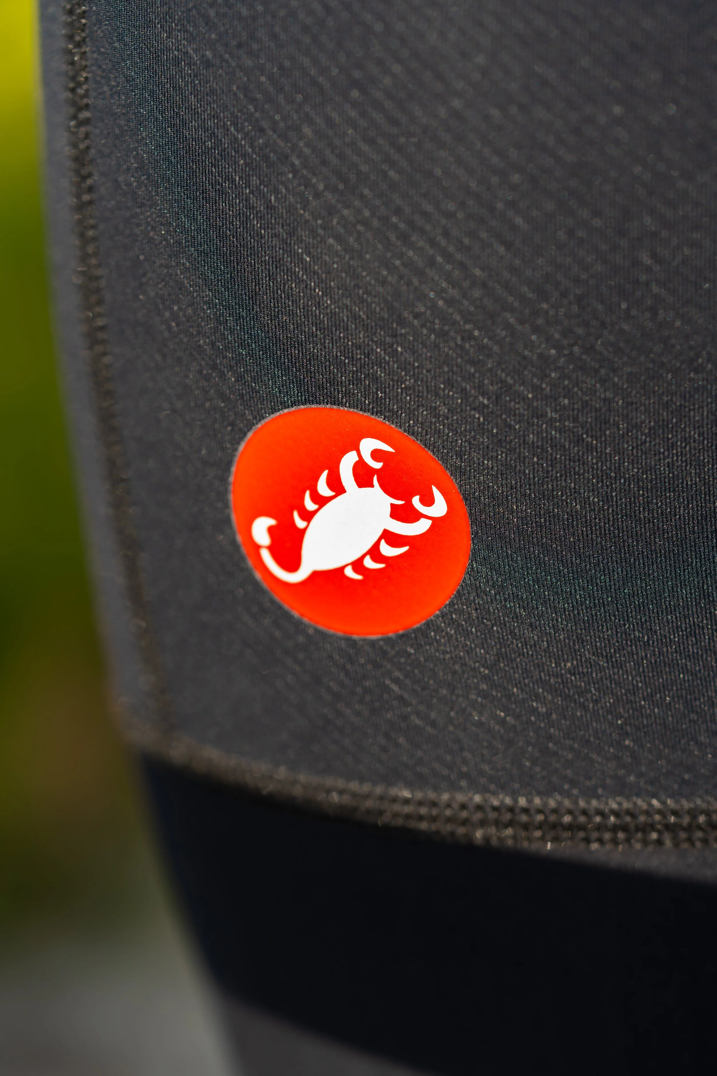 Cerca de un sticker redondo con un cangrejo blanco en un fondo naranja, en una superficie de tela negra