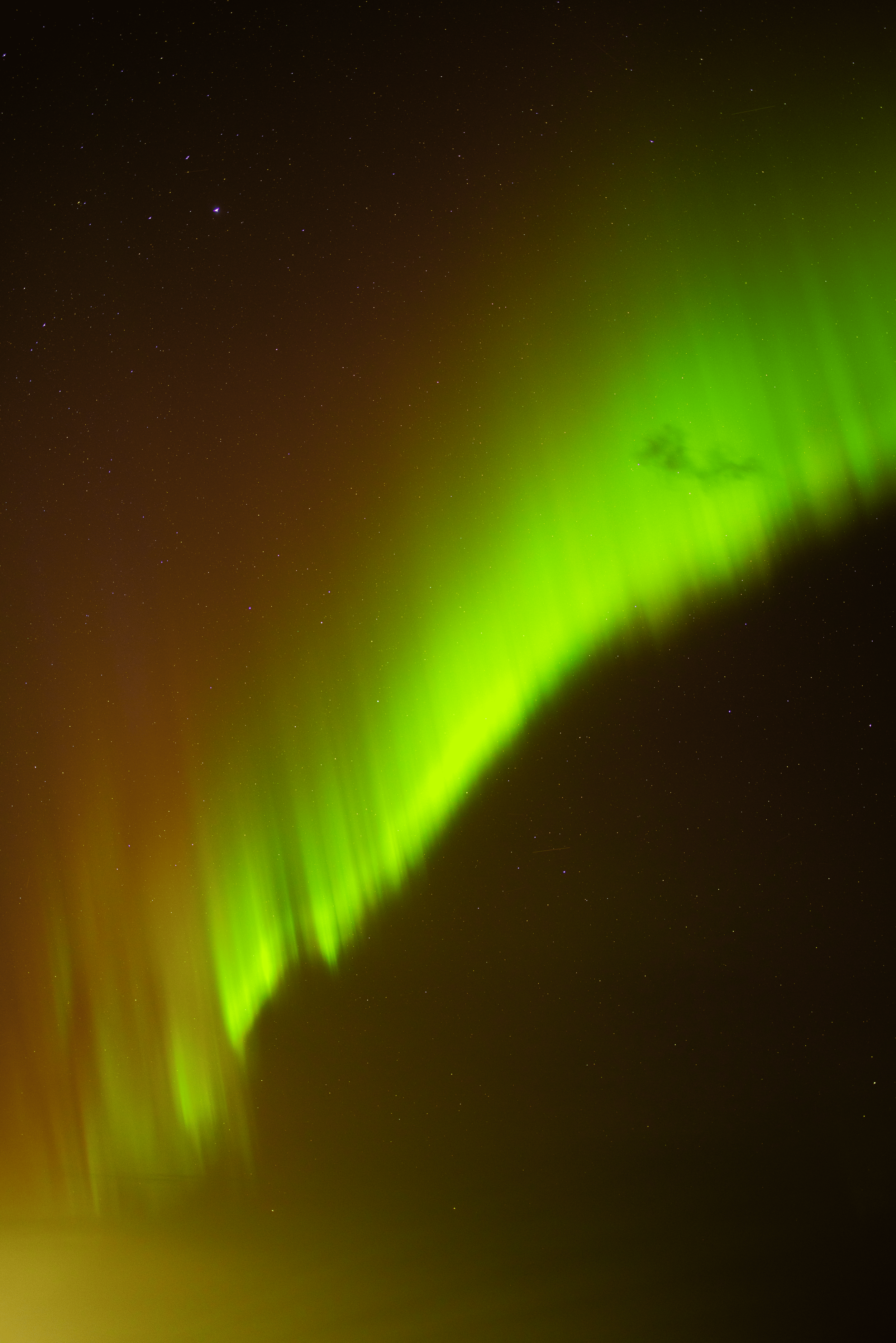 Aurora boreal en el cielo nocturno con estrellas visibles.