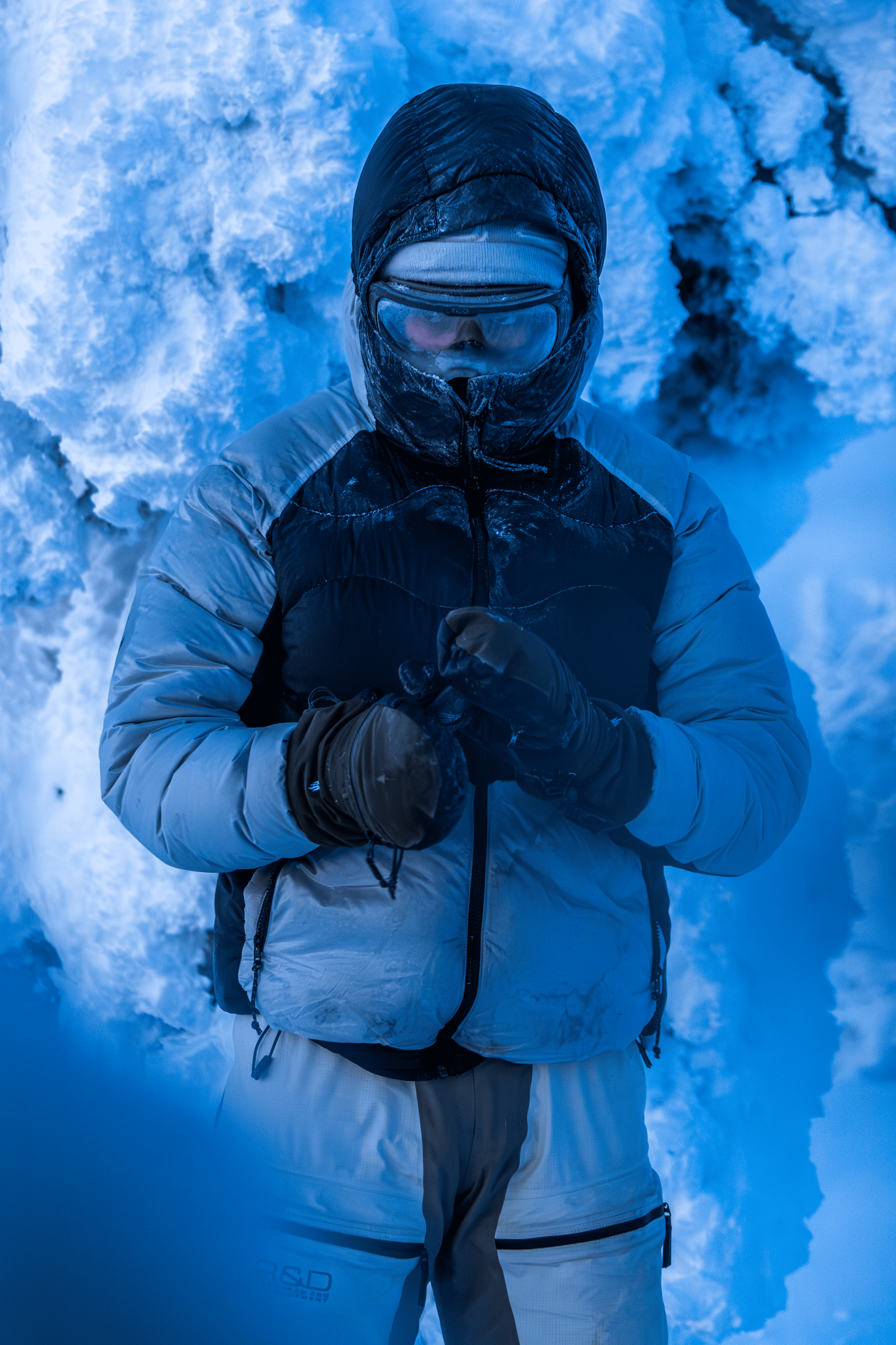 Persona abrigada con chaqueta y gafas en un entorno de nieve.