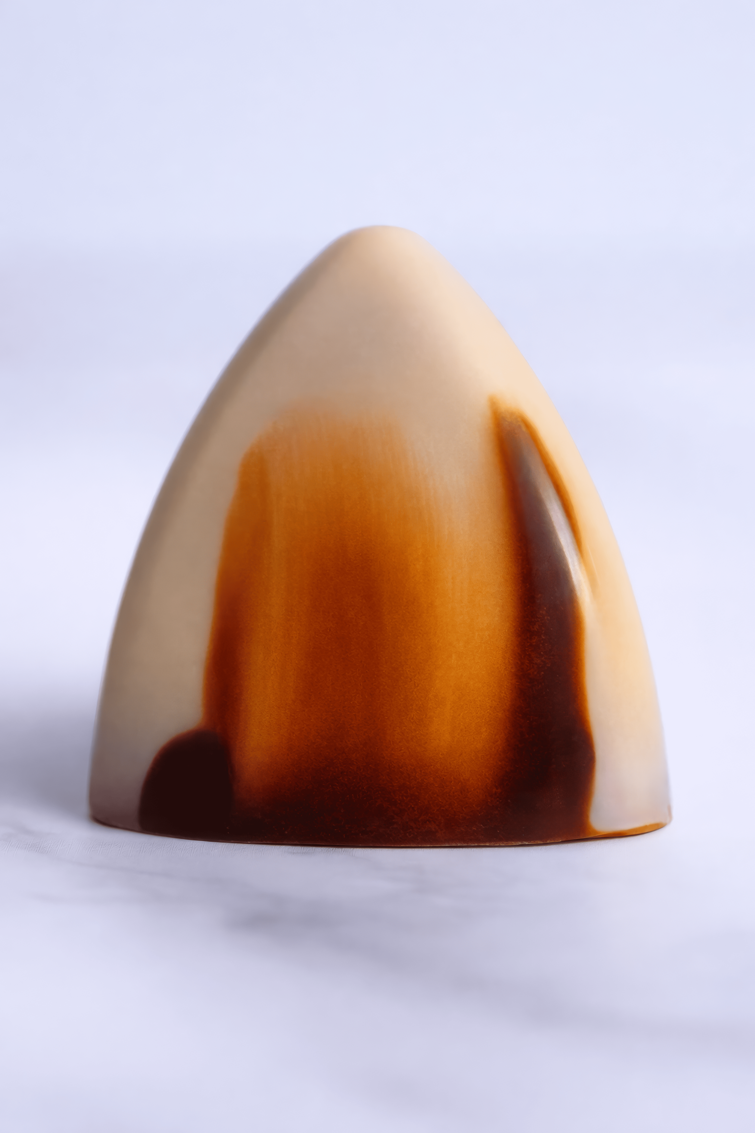 Un trozo de chocolate en forma de montaña con tonos blancos, marrones y beige