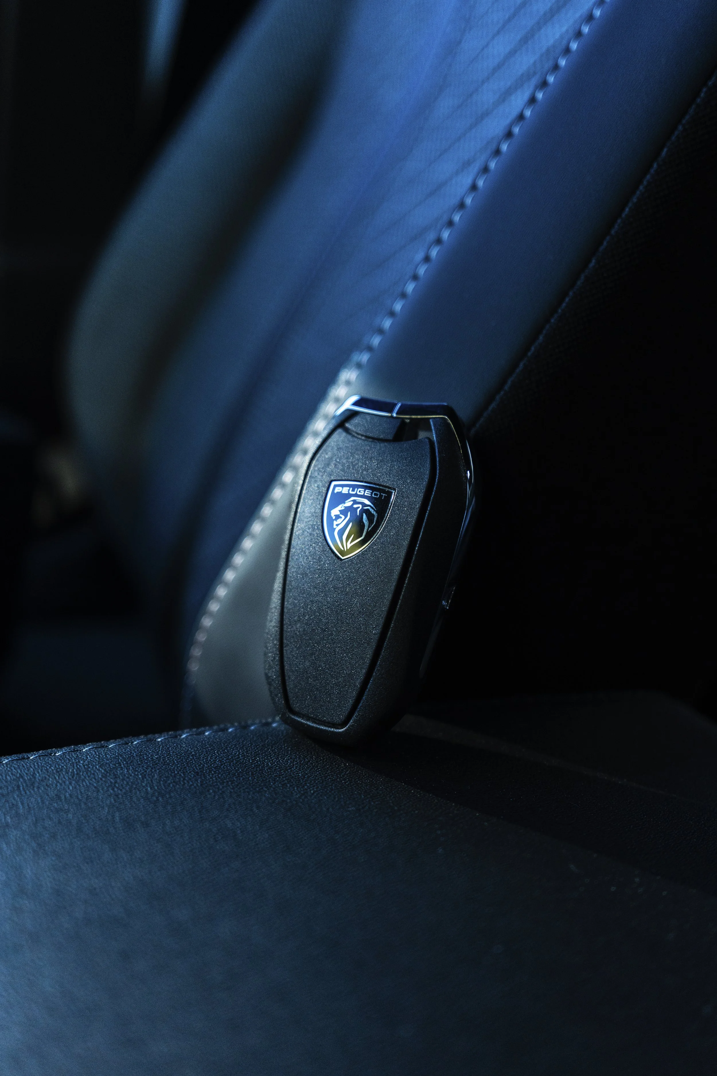 Cierre de seguridad en un asiento de coche con logo de Peugeot, en un interior de coche con detalles en cuero negro