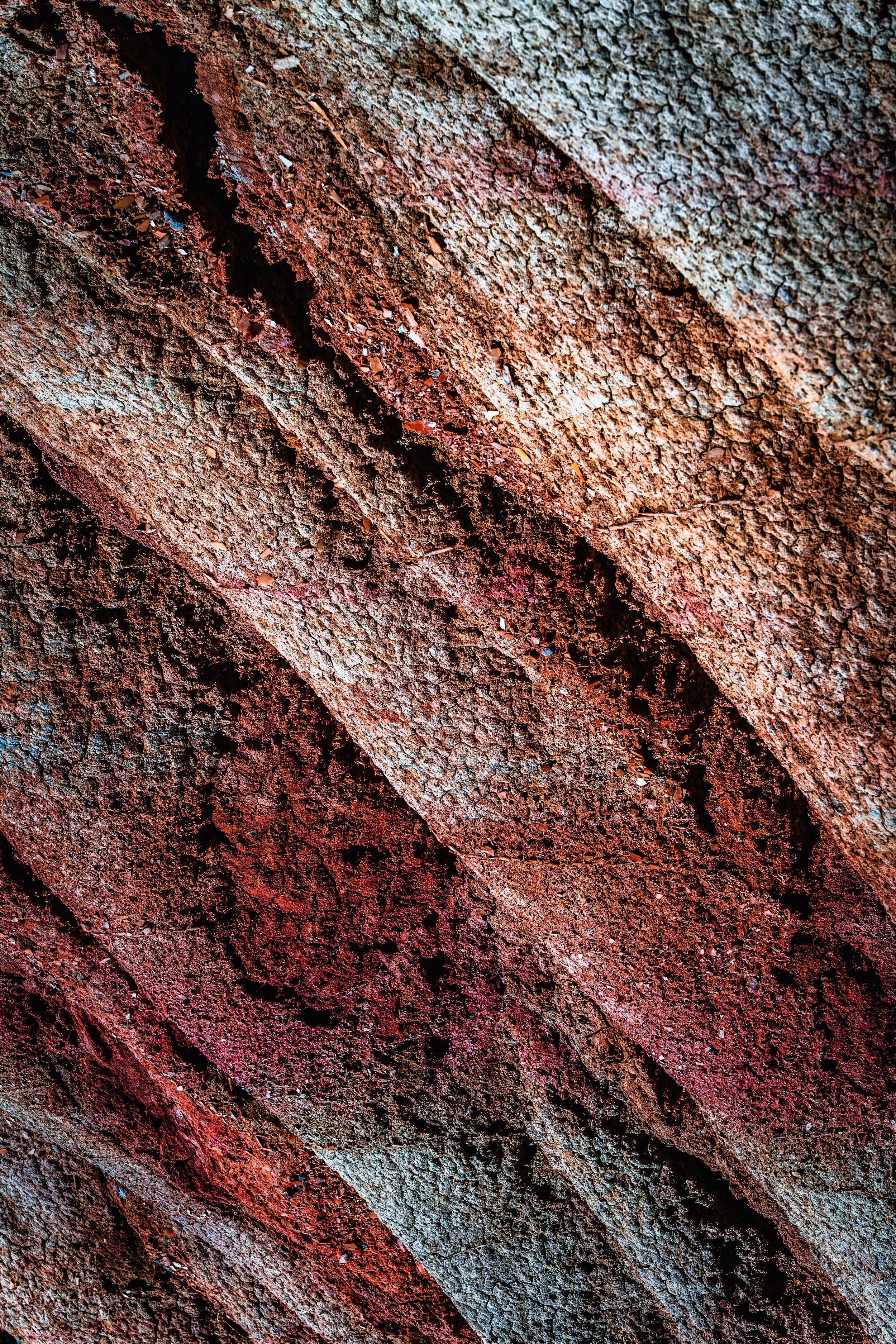 Textura de roca con colores rojos, marrones y tonos naranjas, con superficie áspera y fissuras.