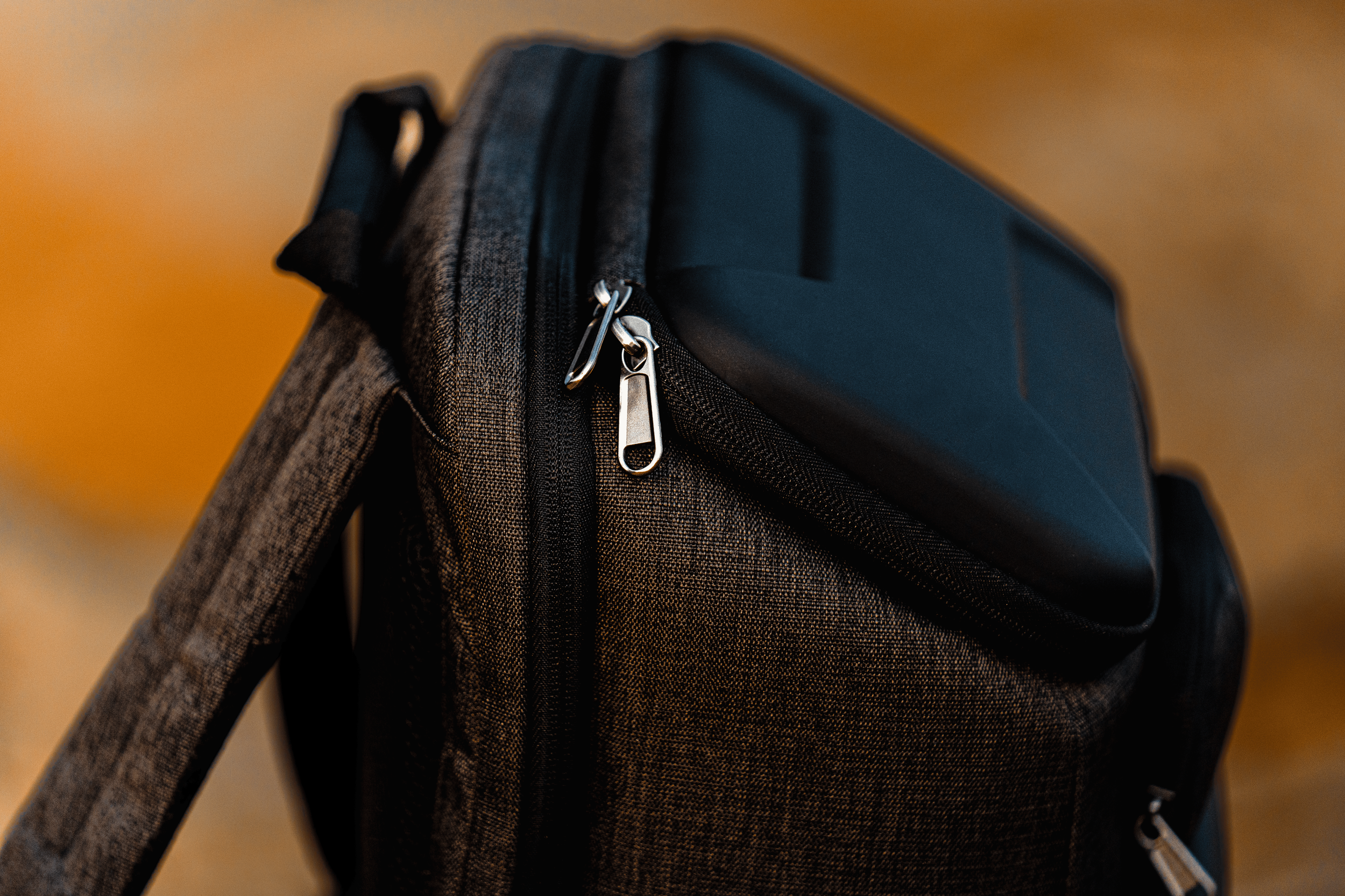 Mochila de tela oscura con un dispositivo electrónico en el bolsillo superior.