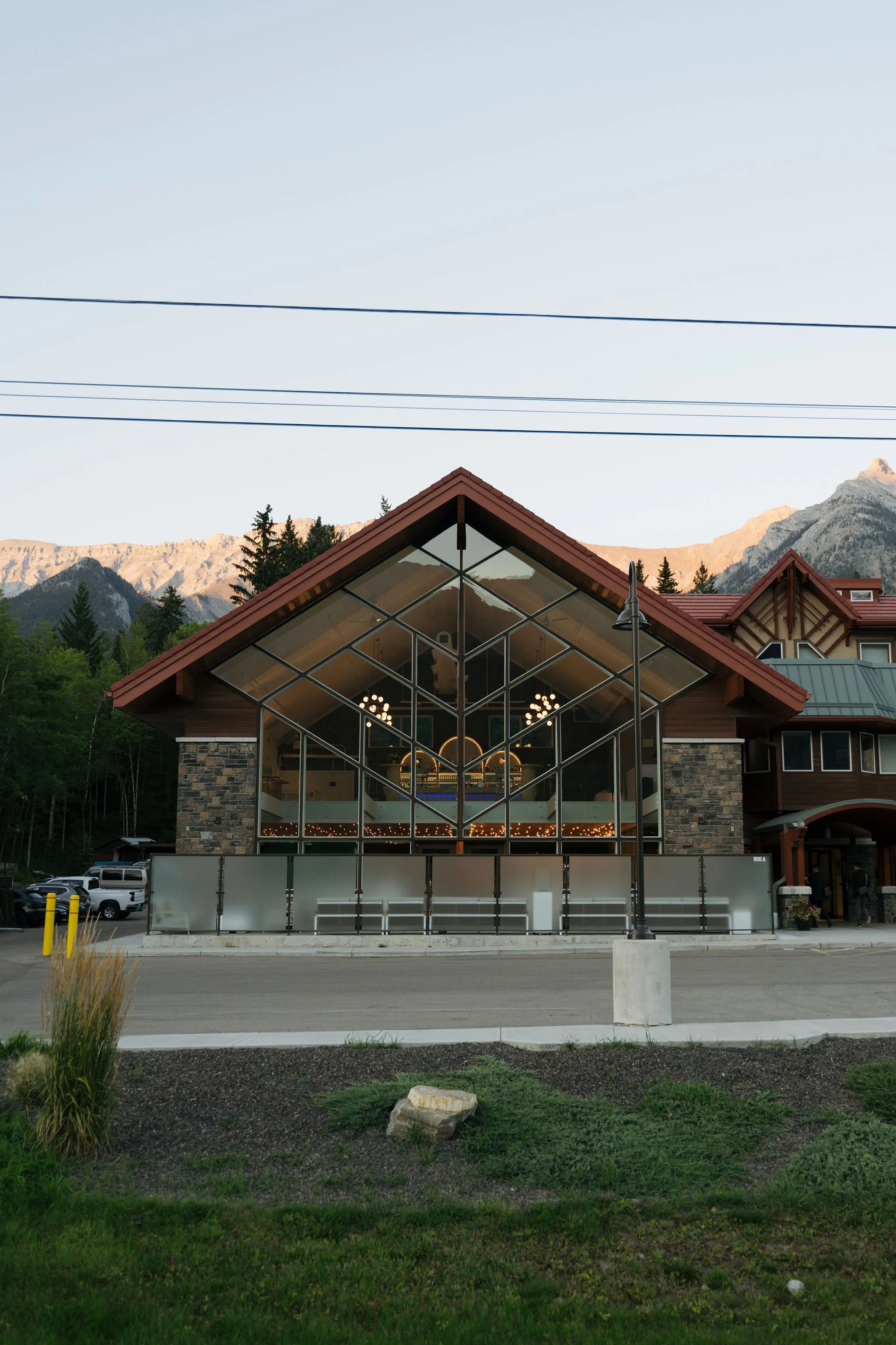 Exterior shot of The Gem wedding venue in Canmore, Alberta—showcasing its dramatic A-frame glass architecture, nestled in the Canadian Rockies. Ideal for modern mountain weddings with scenic charm.