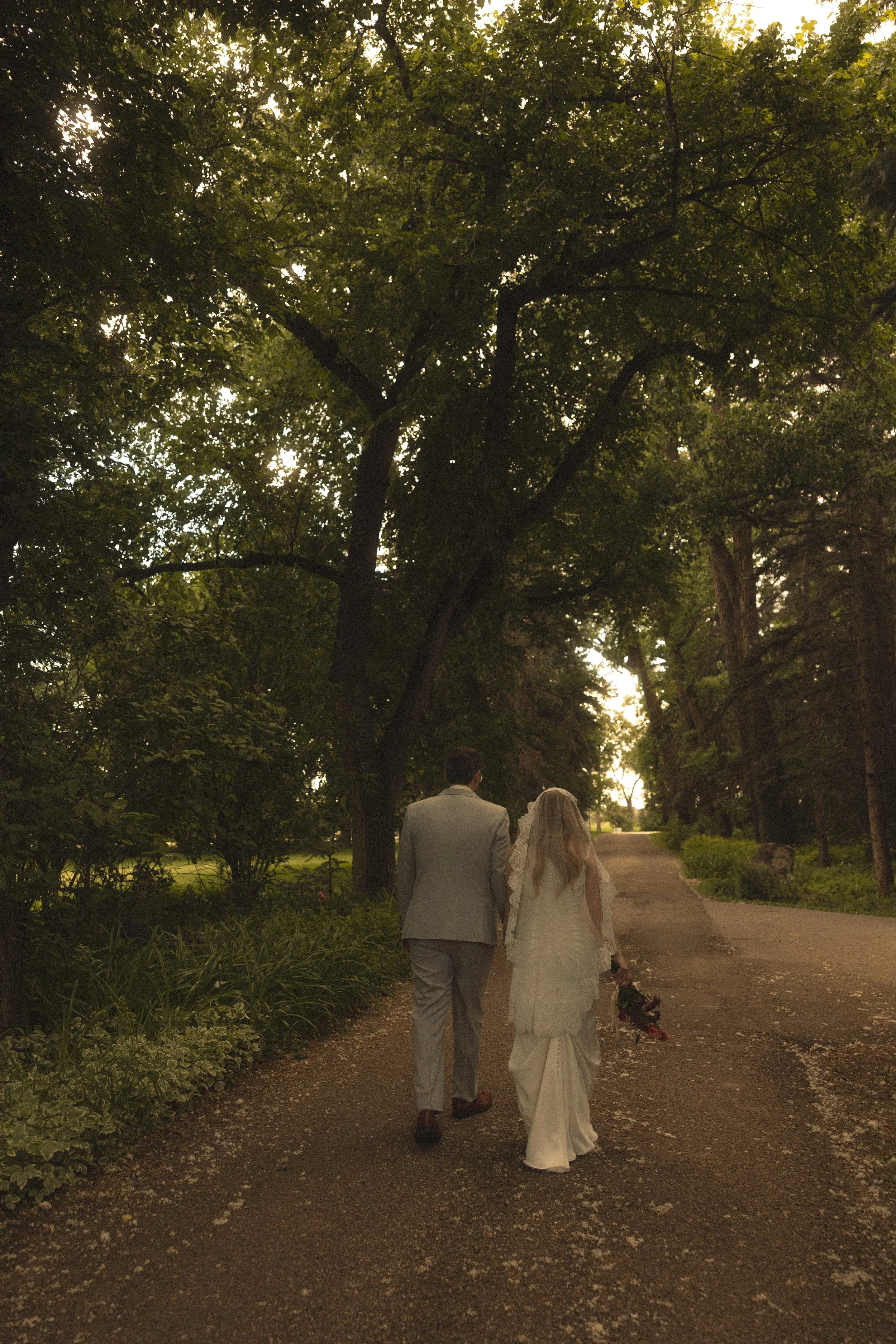 bride and groom walking in nature, surrounded by trees