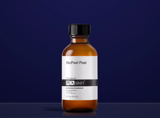 A brown glass bottle labeled 'NoPeel Peel' with a black screw cap, standing on a dark surface against a navy blue background.