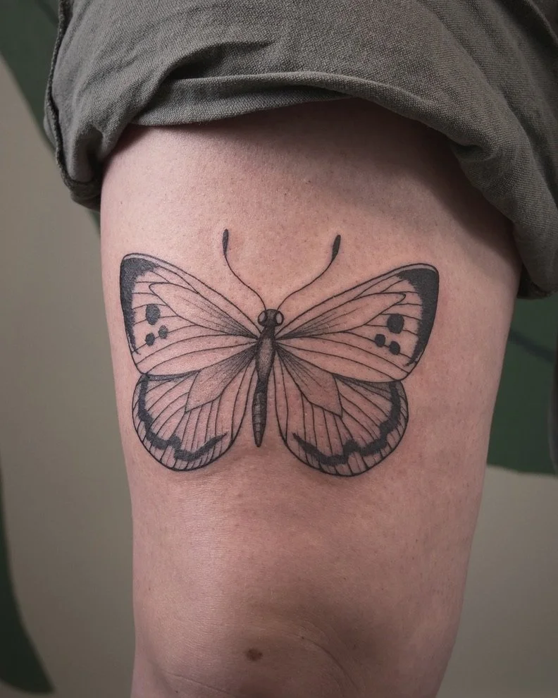 Black ink butterfly tattoo on person's upper thigh.