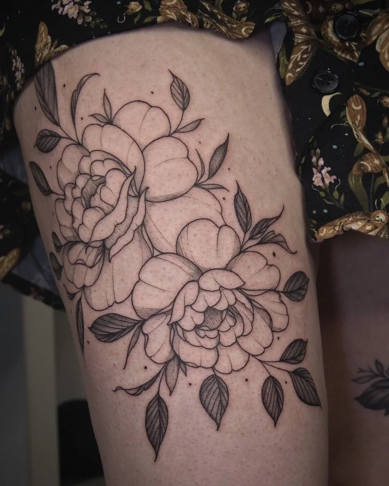 Outline floral tattoo on person's thigh featuring large roses and leaves.