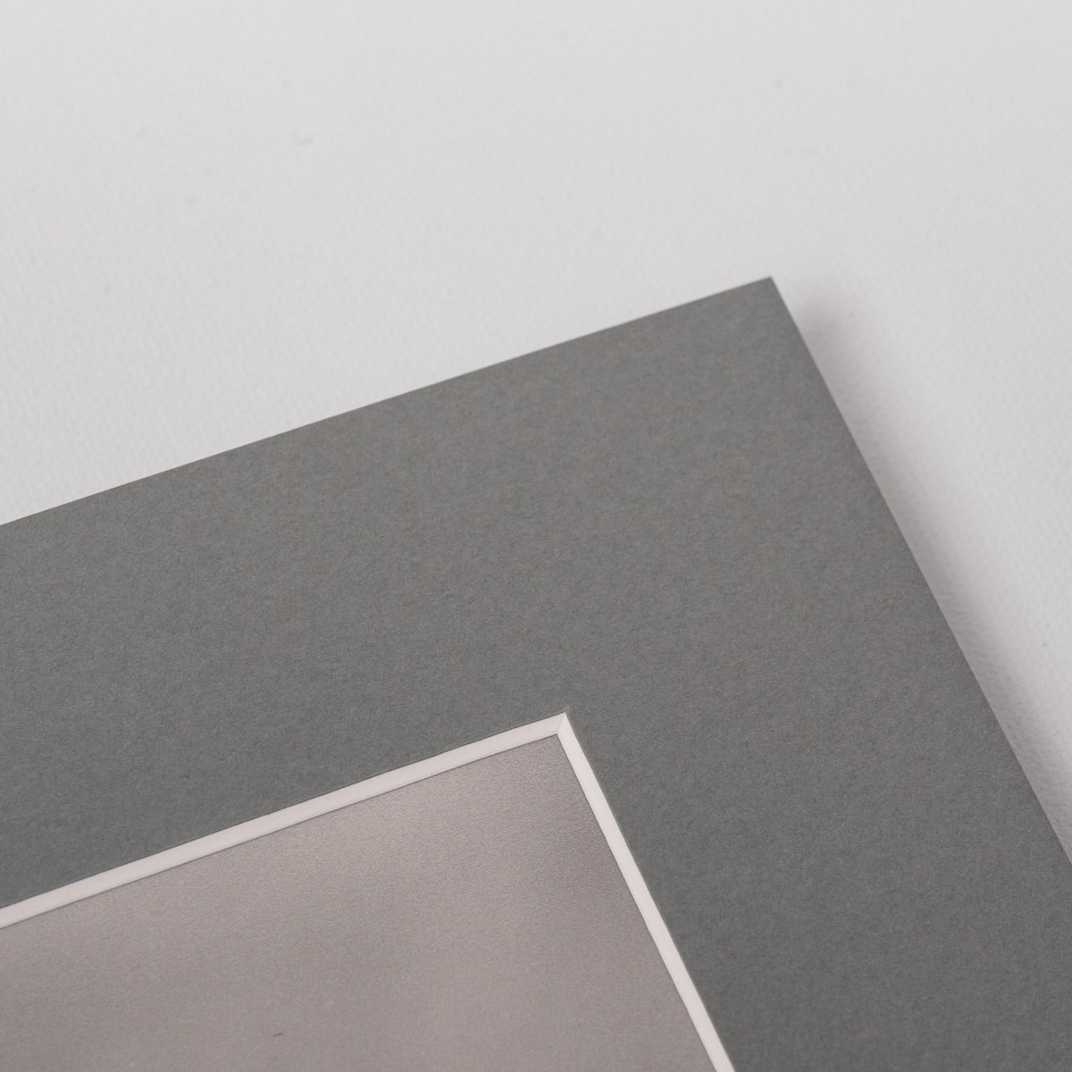 Close-up detail of a black and white fine art print with soft grey mat board, showing paper texture and clean professional finish