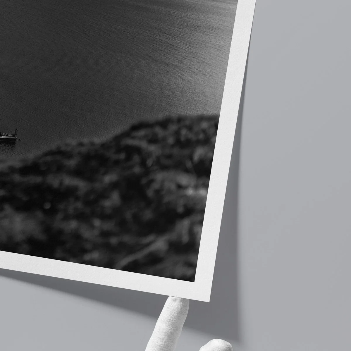 Close-up of a fine art print edge held by hand, showing paper texture and white border in a minimalist setting.