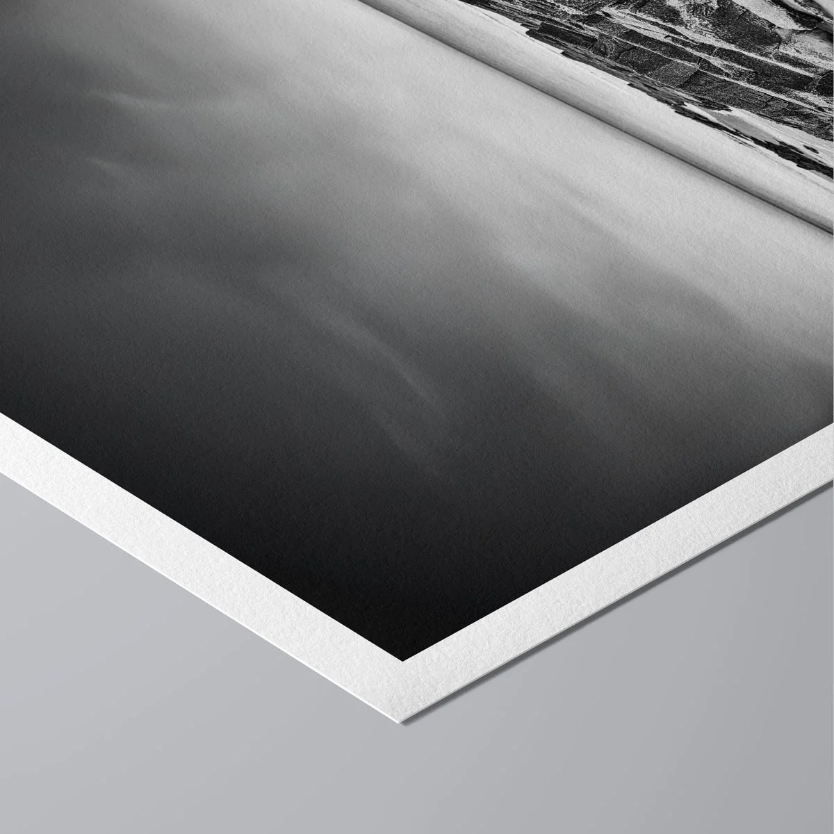 Angled view of a black and white coastal print highlighting the white border and paper surface.
