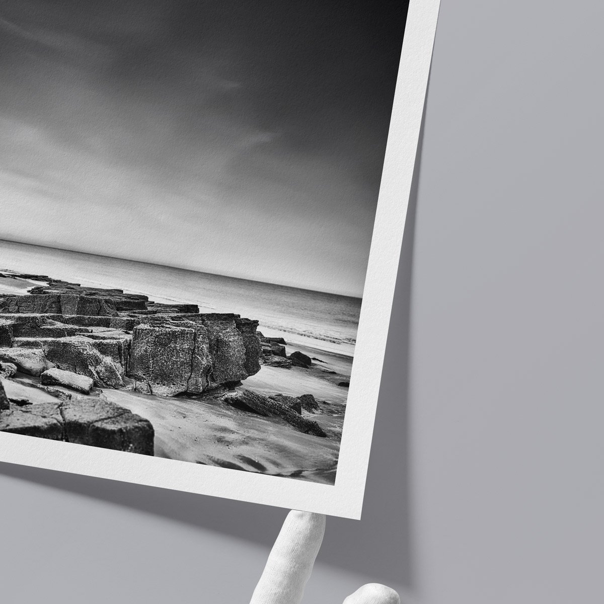 Detail view of a black and white fine art print on textured paper, gently held by hand.