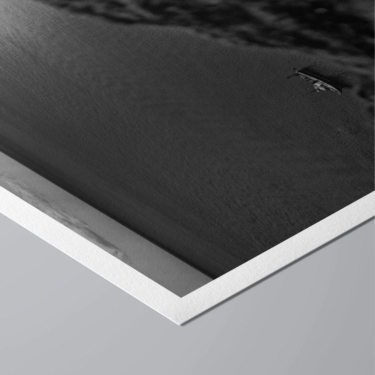 Angled close-up of a black and white fine art print showing layered paper edges and minimalist presentation.