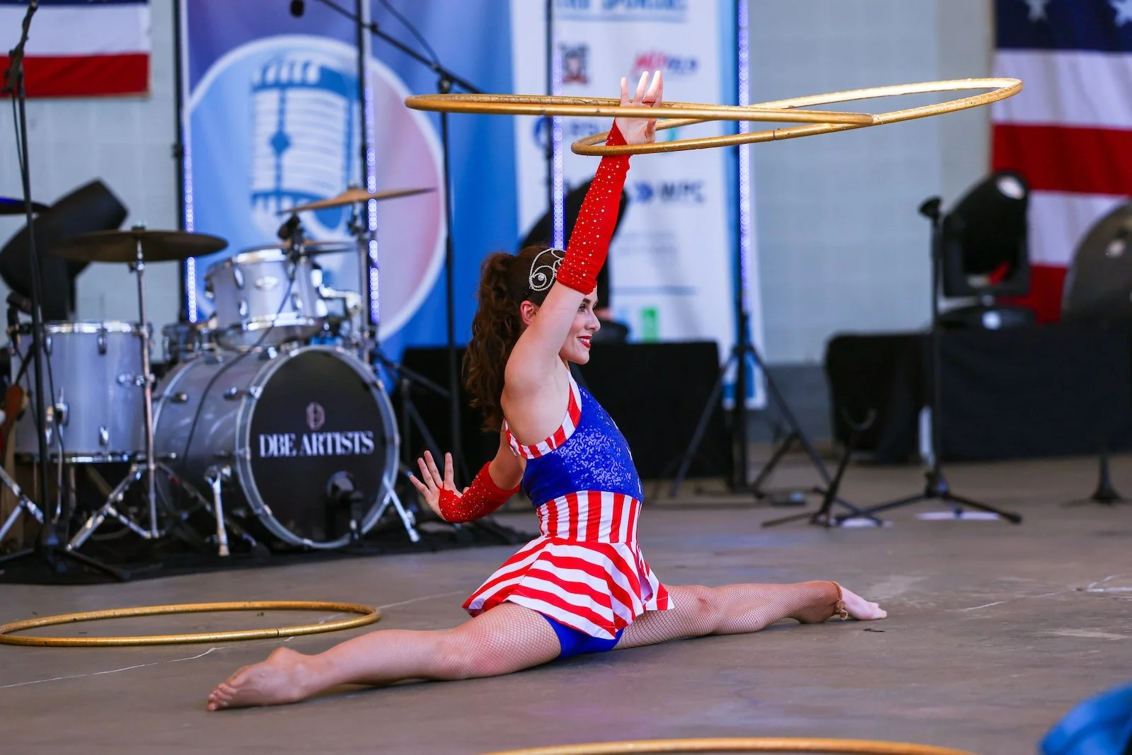 Patriotic hula hoop performer doing the splits during a live stage performance at Red, White & BOOM in Brentwood, Tennessee.