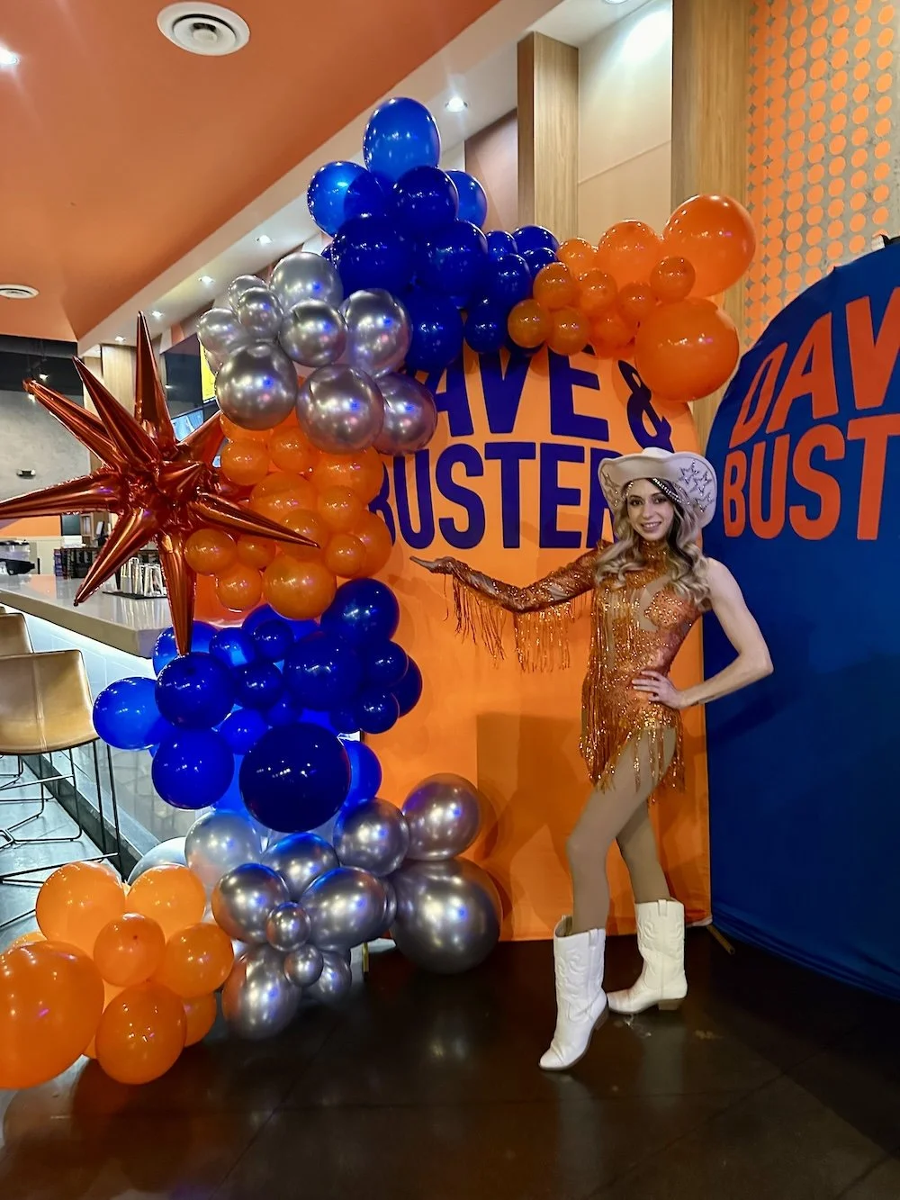 Performer posing in front of the Dave & Buster's grand reopening balloon arch in Nashville.
