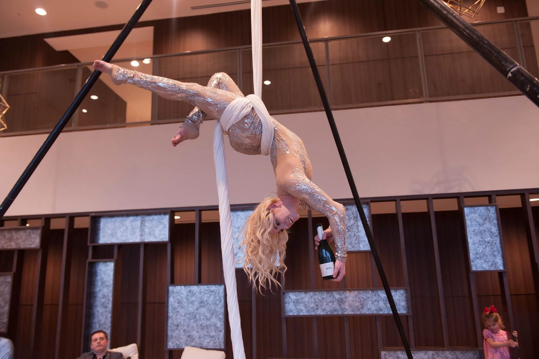 aerialist with champagne bottle serving upside-down