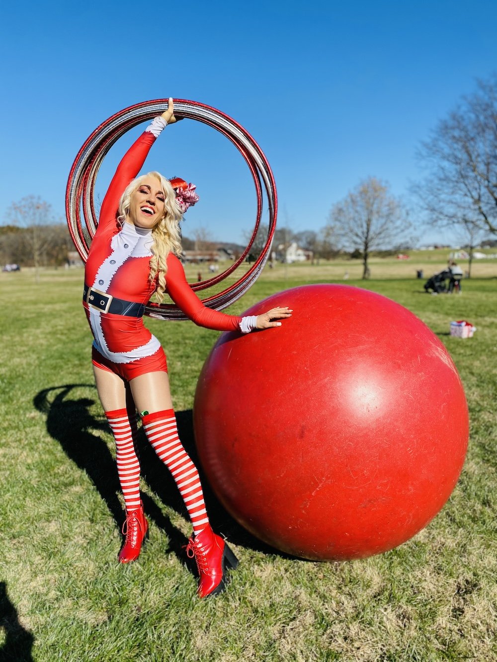 Holiday cirque performer in a Santa costume with hula hoops and a giant red ball
