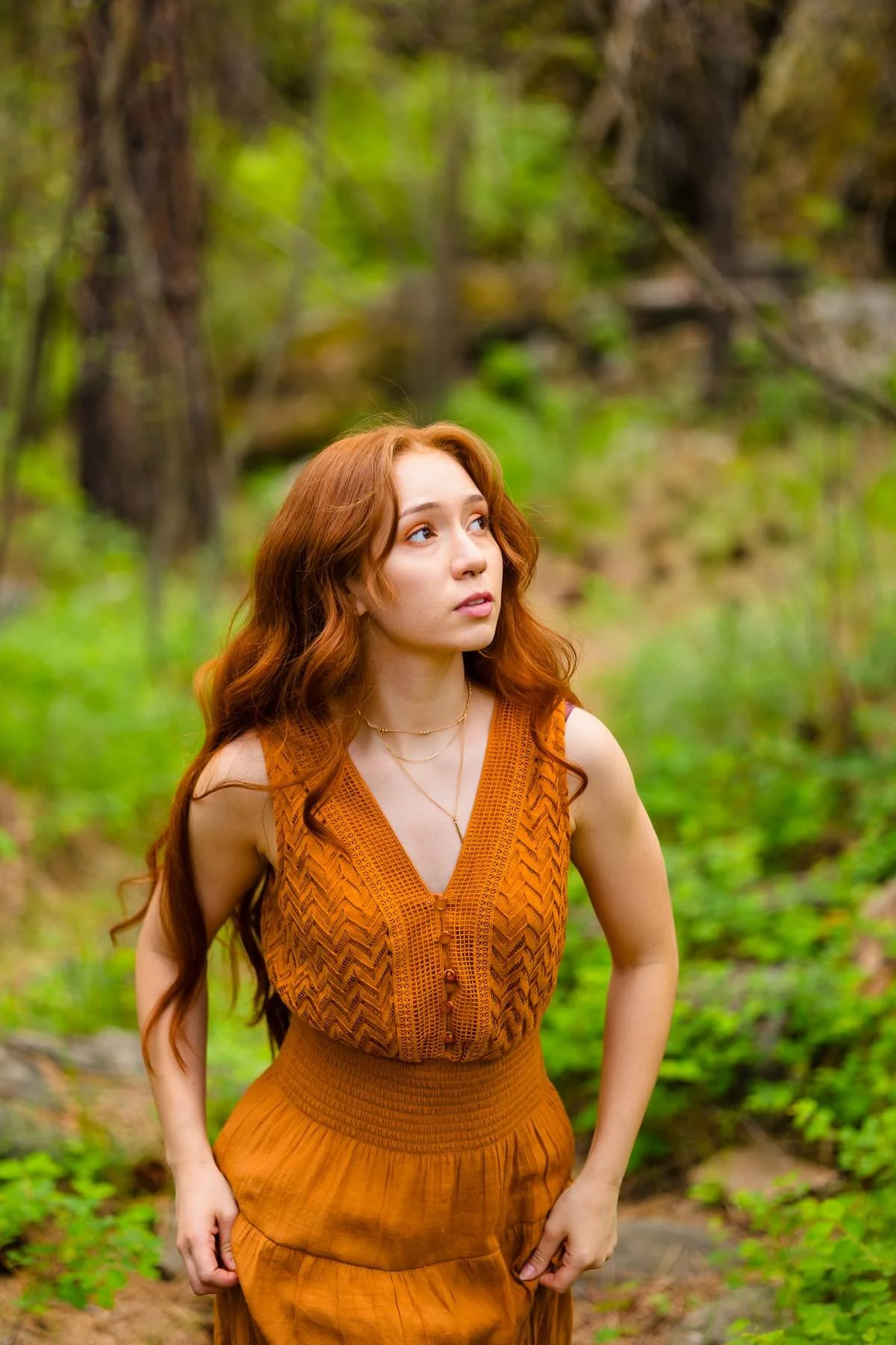 Red head girl in red dress exploring the forest