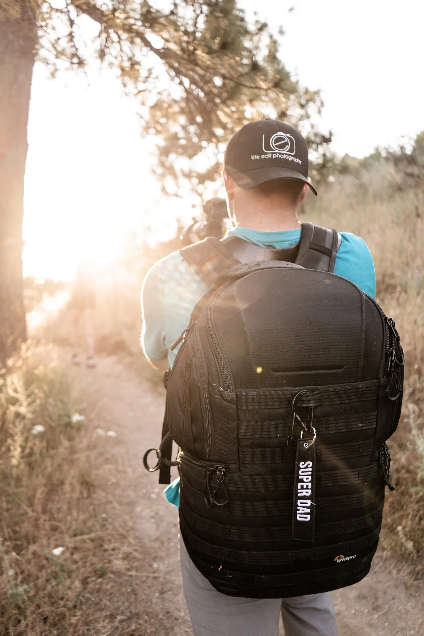 A behind the scenes picture of the photographer of life edit photography taking a picture at golden hour. The photo is taken of his back with the golden light casting into his face.