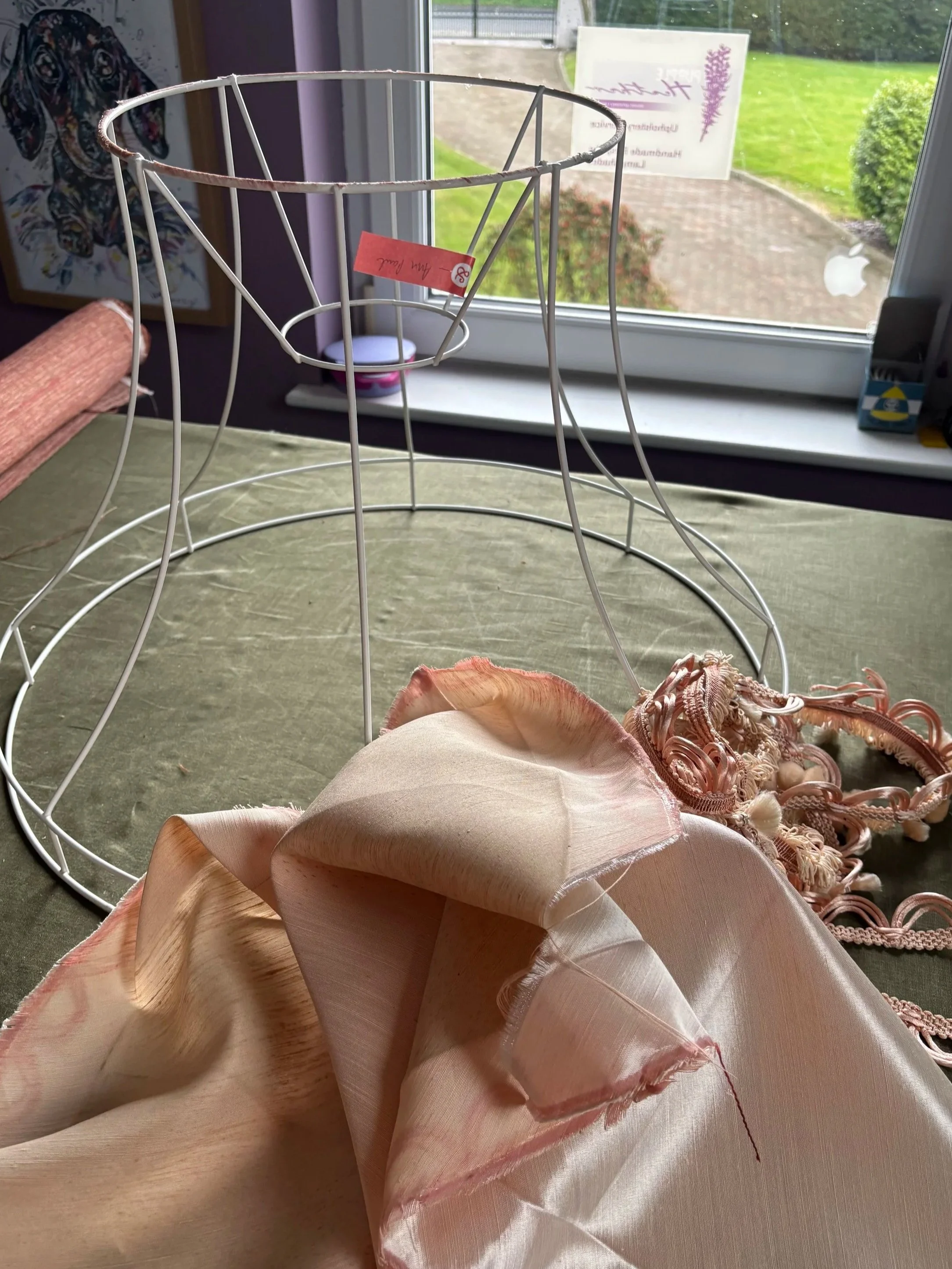 bowed vintage lampshade deconstructed to frame. old fabric lying beside the frame.
