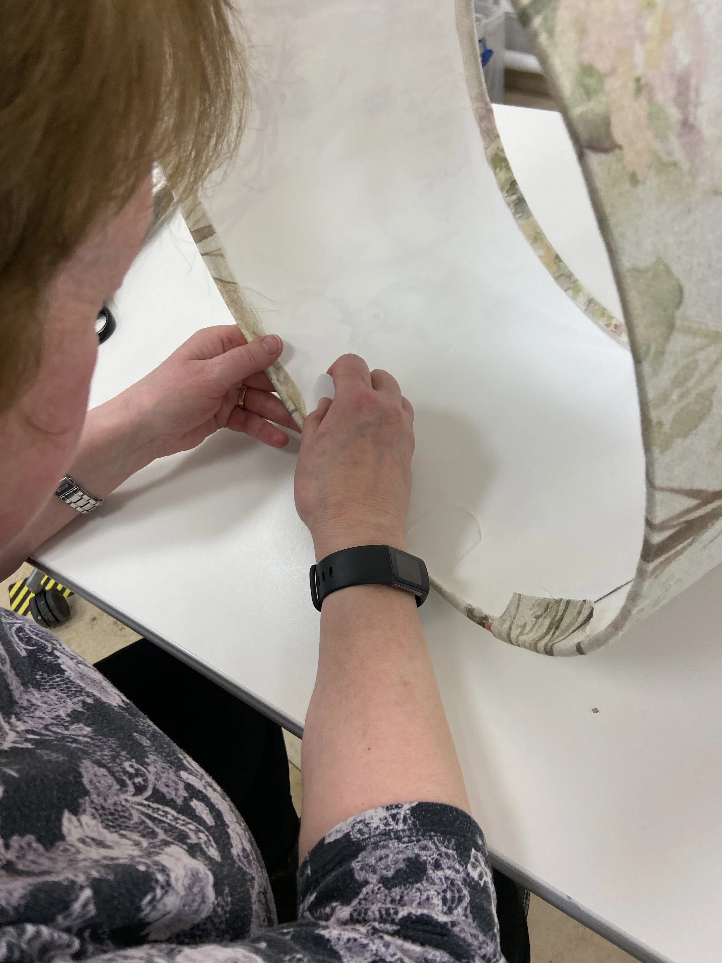 A person tucking fabric into the lampshade rings while attending a lampshade making workshop