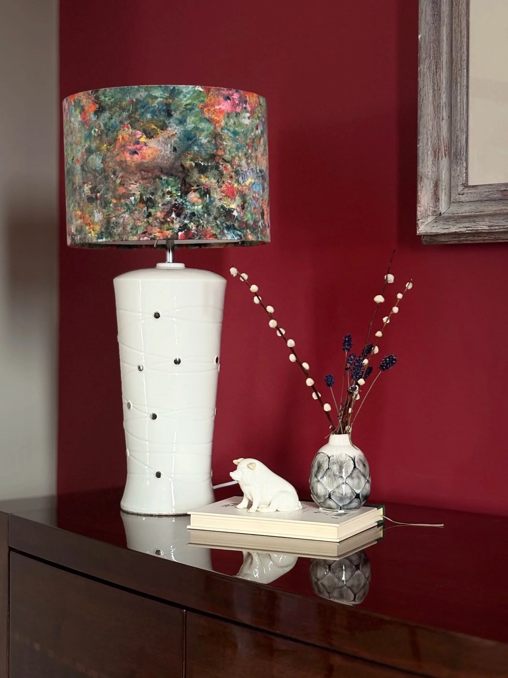 Decorative table arrangement featuring a tall white ceramic lamp base, a colourful abstract patterned lampshade. Lampshade handmade by a person who attended a lampshade making workshop 