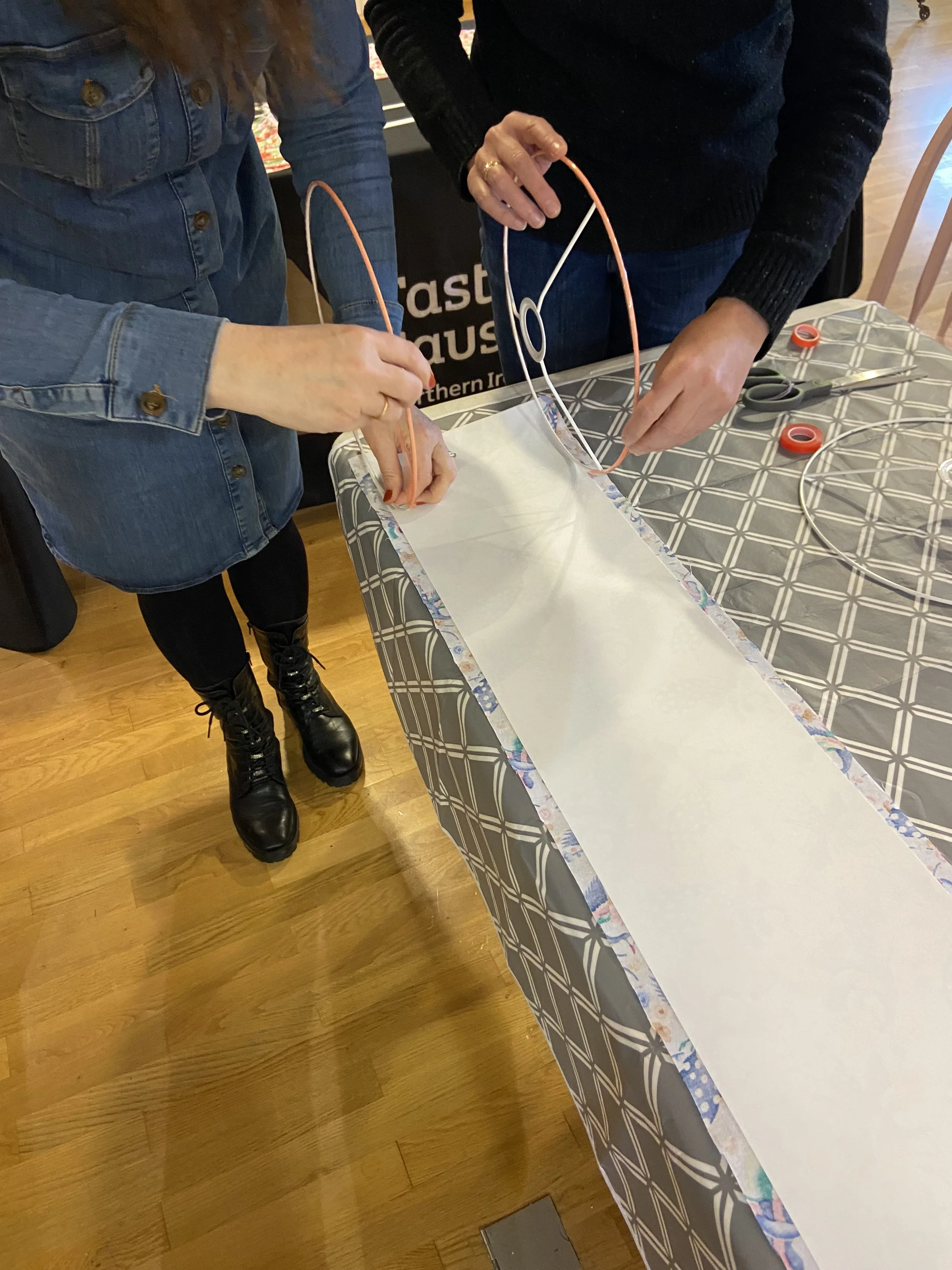 Two people working together to make a lampshade in a workshop