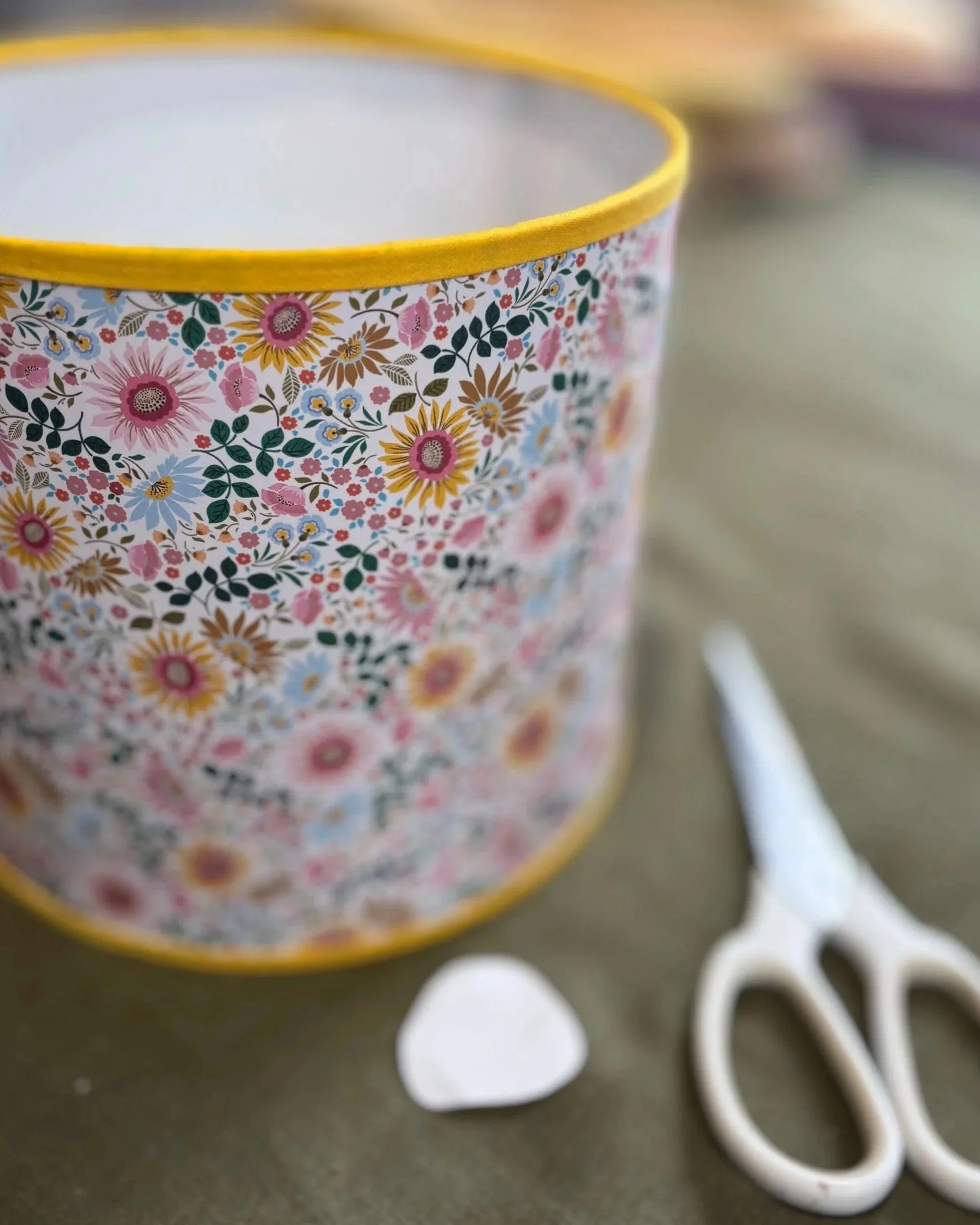 Close-up of a floral patterned paper lampshade with yellow bias binding trim on top and bottom