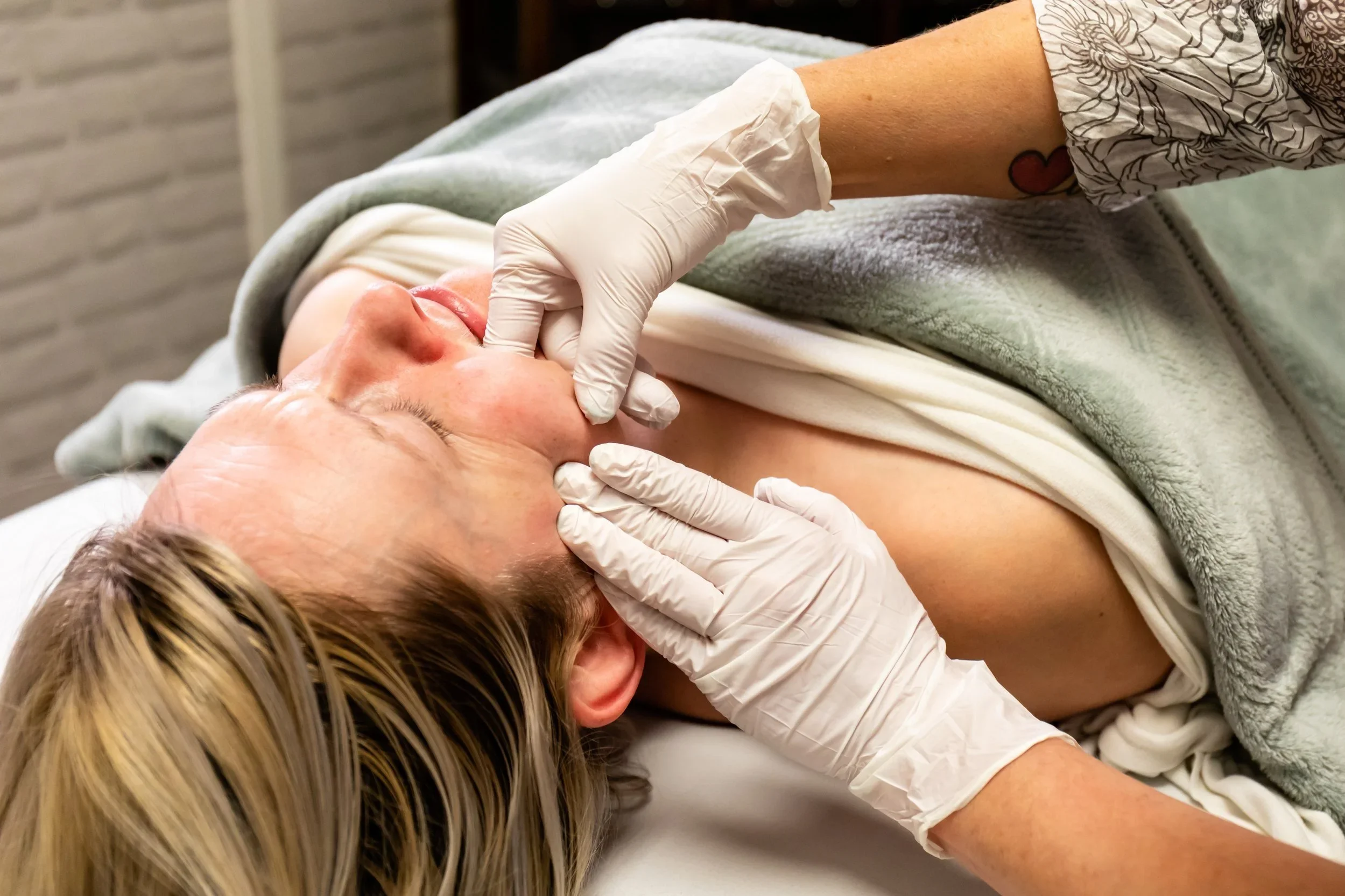 Client relaxing during a facial and jaw massage with a registered massage therapist in Fraser Heights, Surrey