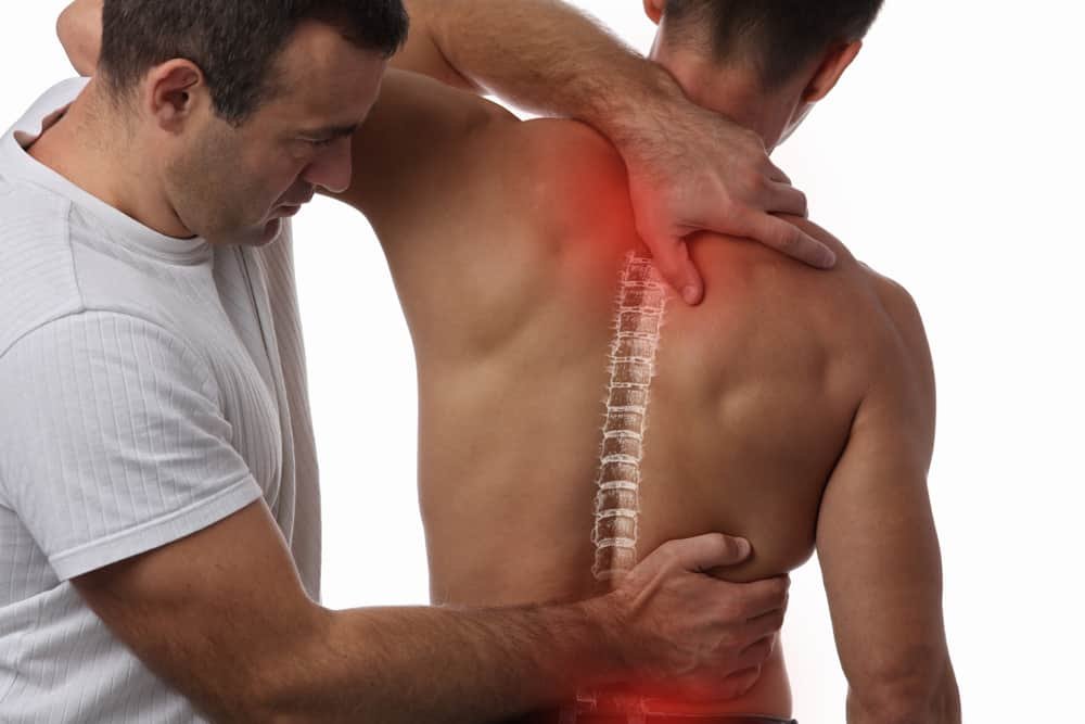 Chiropractor assessing a patient's upper back and shoulder pain along the spine
