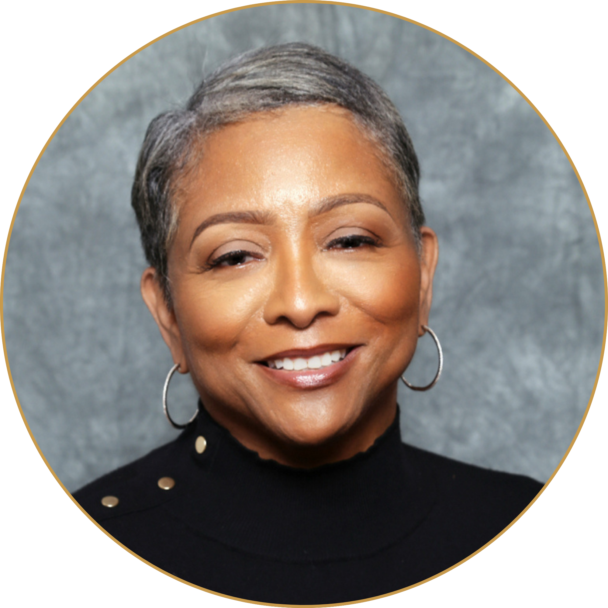 Close-up of a smiling woman with short gray hair, wearing hoop earrings and a black top with gold buttons, against a gray textured background.