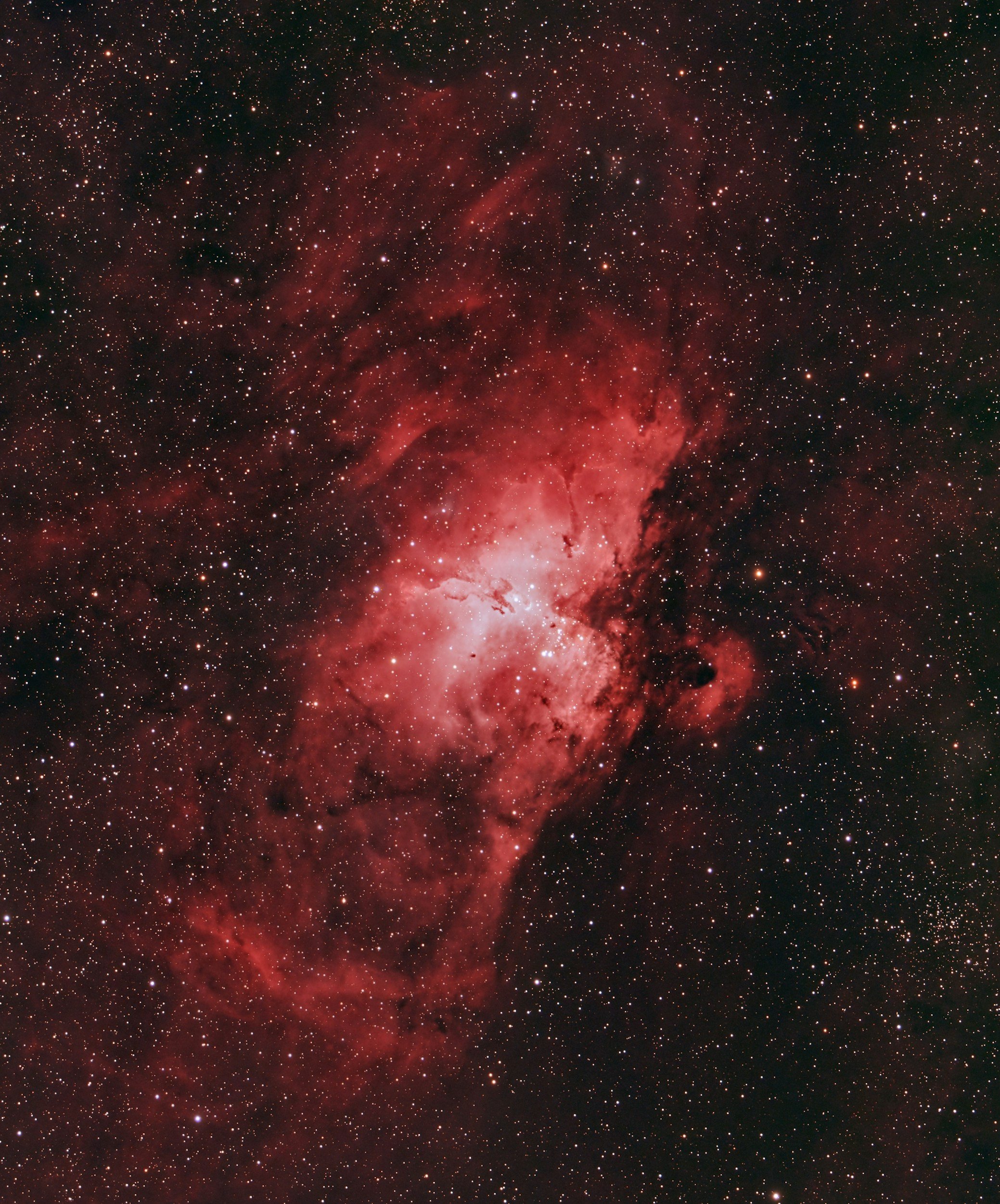 A detailed image of a nebula in space with red and black cloud formations and numerous stars scattered throughout.
