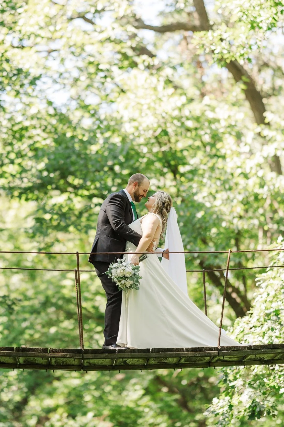 bride and groom meeting in the middle of a suspended bridge as the bride is leaned back for a kiss