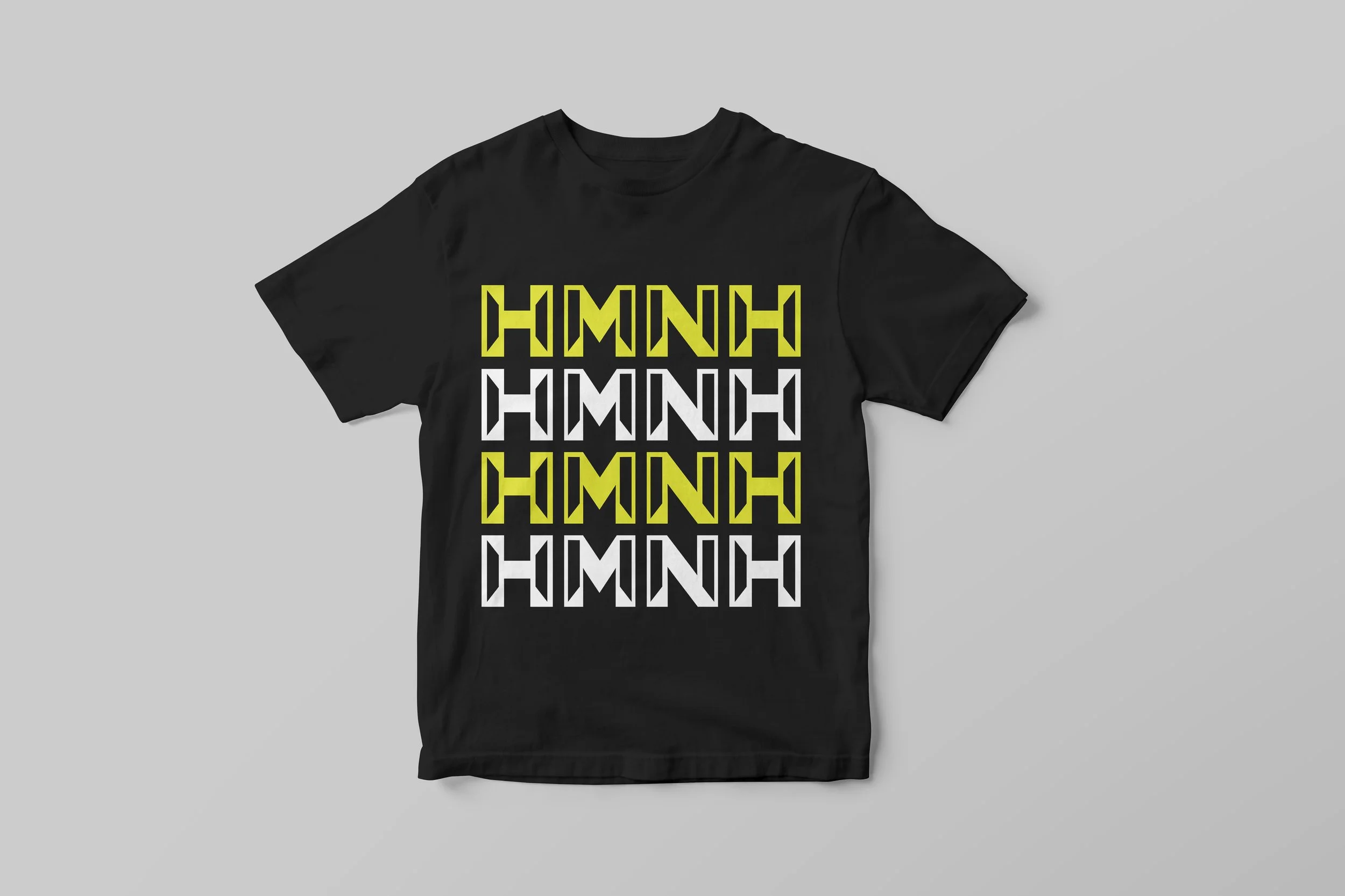 Black T-shirt with a repeating pattern of the word 'HMNH' in yellow and white geometric font.