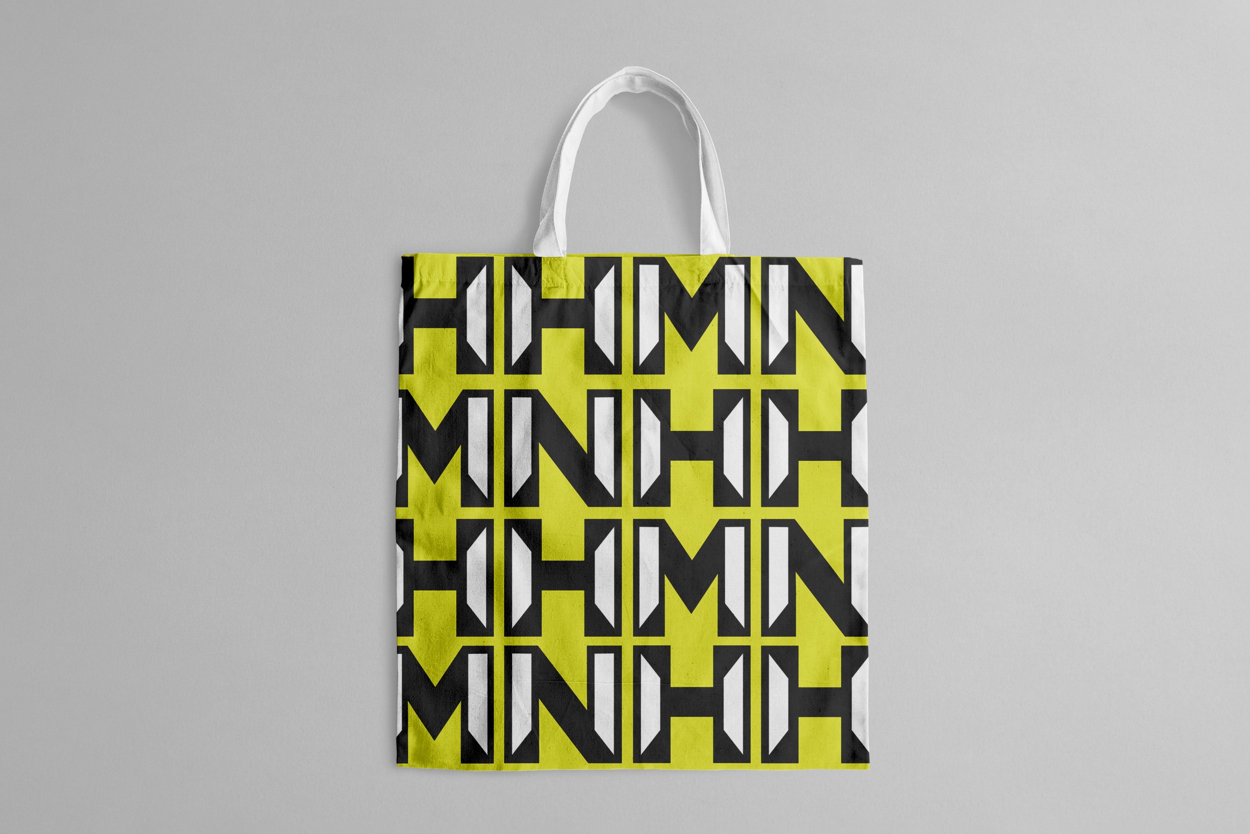 Colorful tote bag with a geometric yellow, black, and white pattern hanging on a wall.