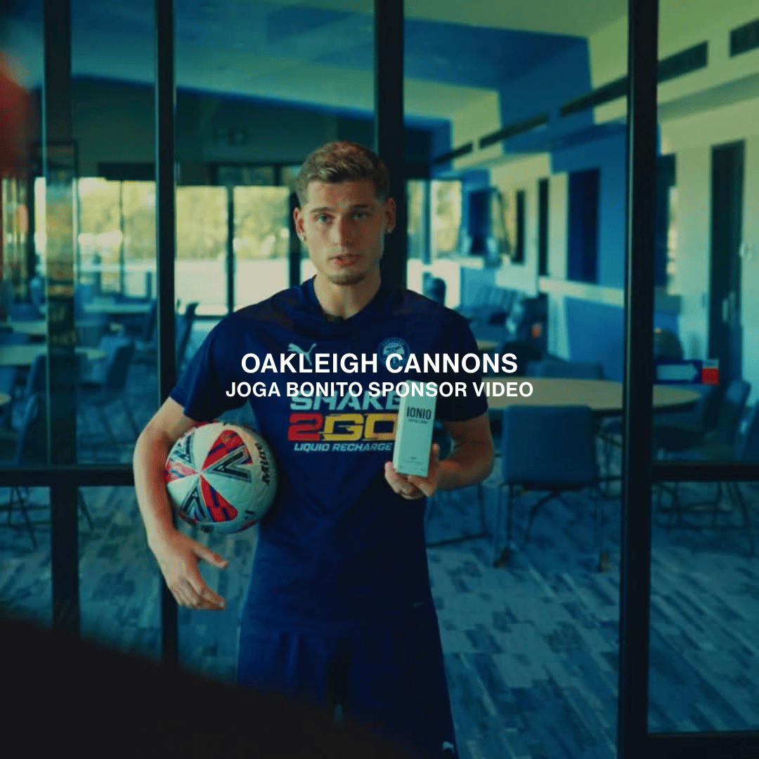 A soccer player with a ball tucked under his arm holding a bottle of IONIO sea salt spray