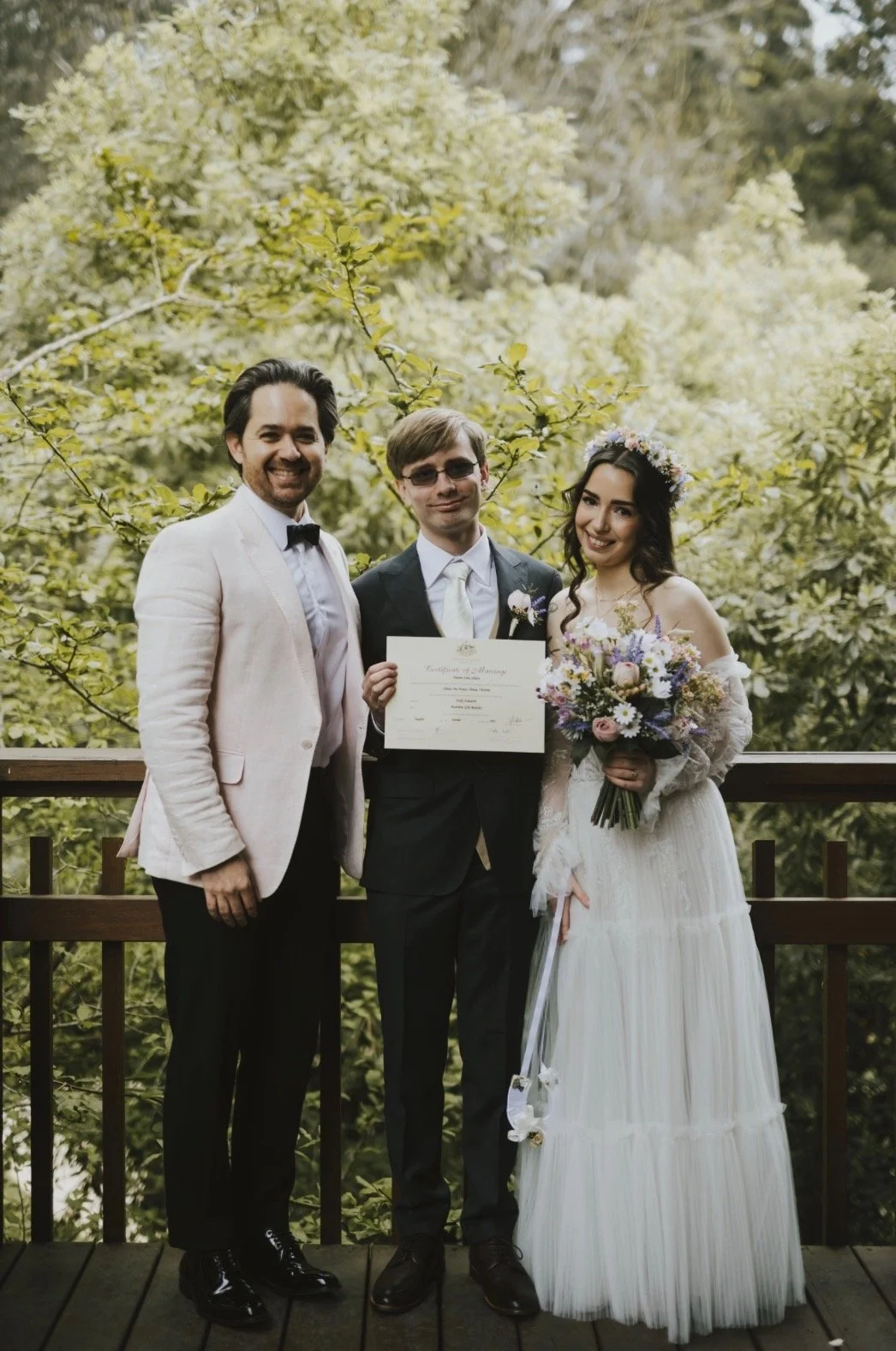 Three people, two men in suits and a woman in a bridal dress