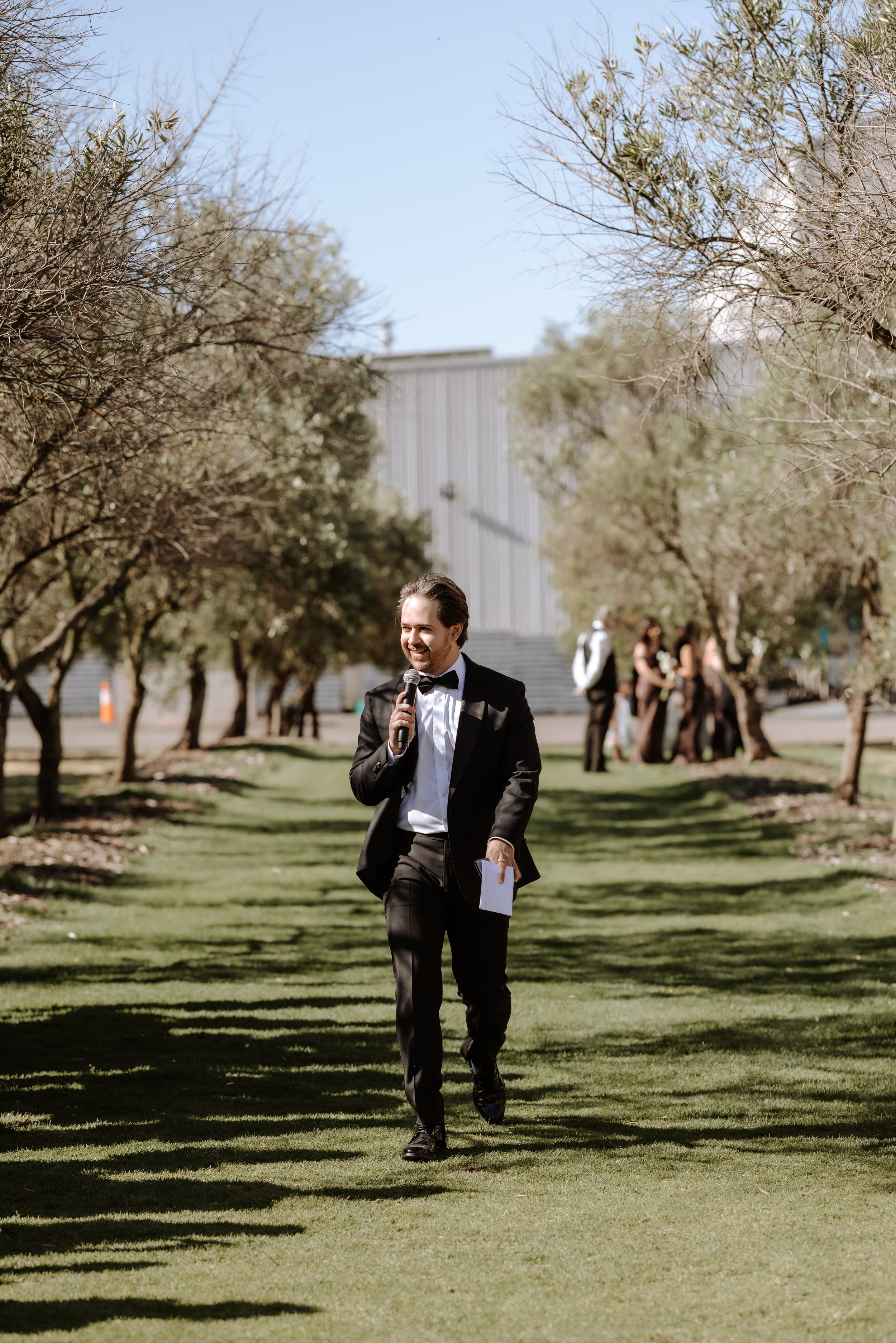 Darren Sibson marriage celebrant with microphone walking down aisle at wedding