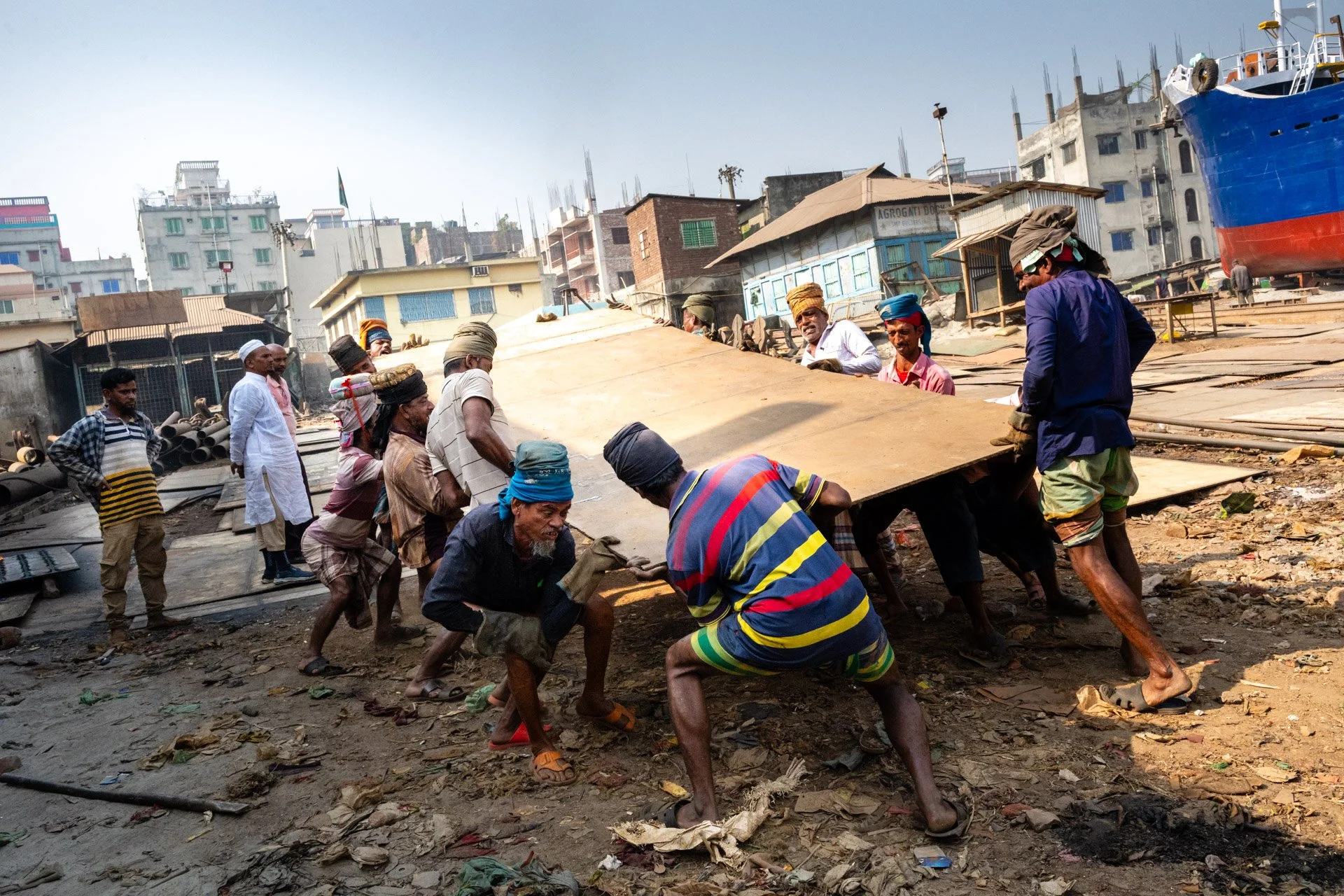 Workers in a shipyard in Dhaka Bangladesh move a heavy piece of steel. 